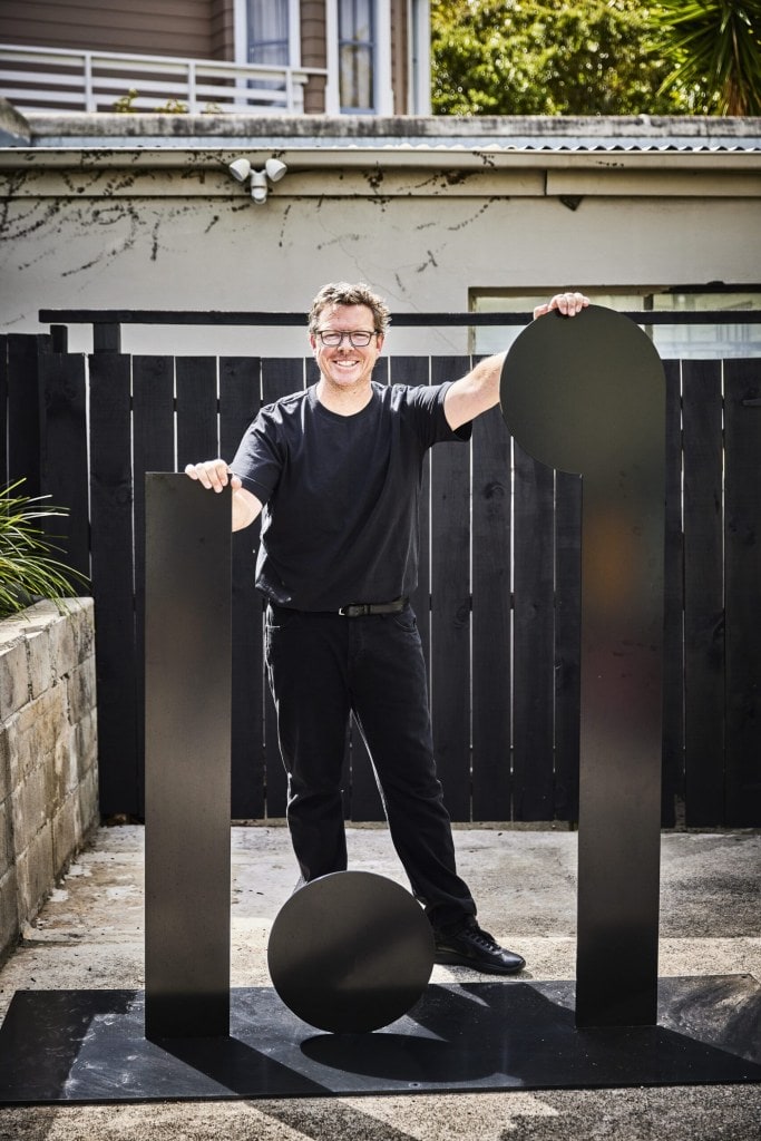 David Alsop standing in courtyard by black art sculptures