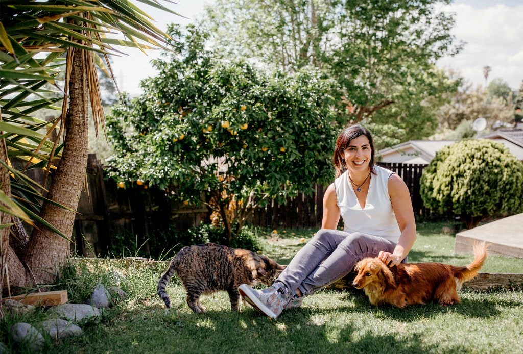 Nadia Sosa sitting under tree with cat and dog