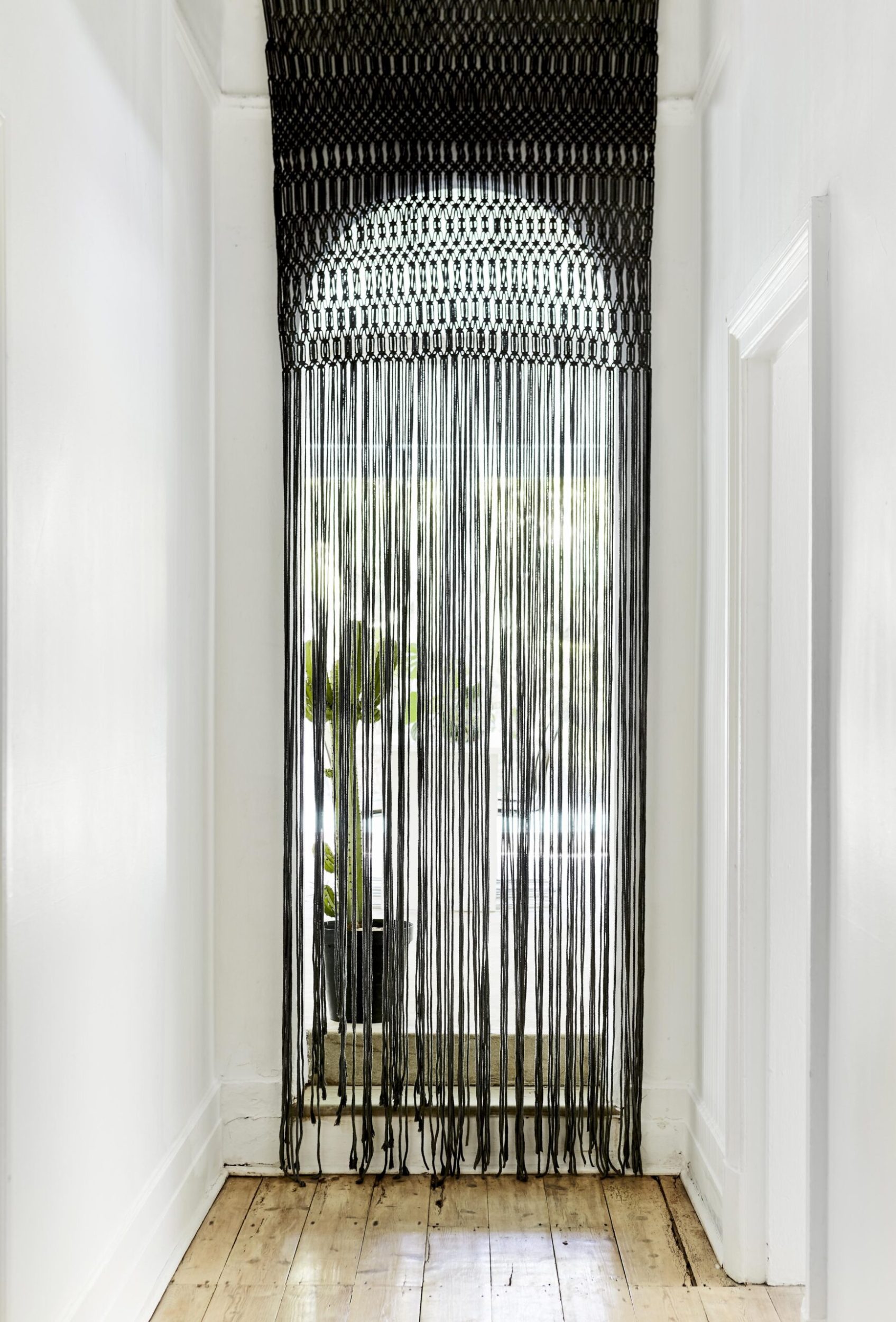 Hall with arched doorway and black macramé curtain hanging