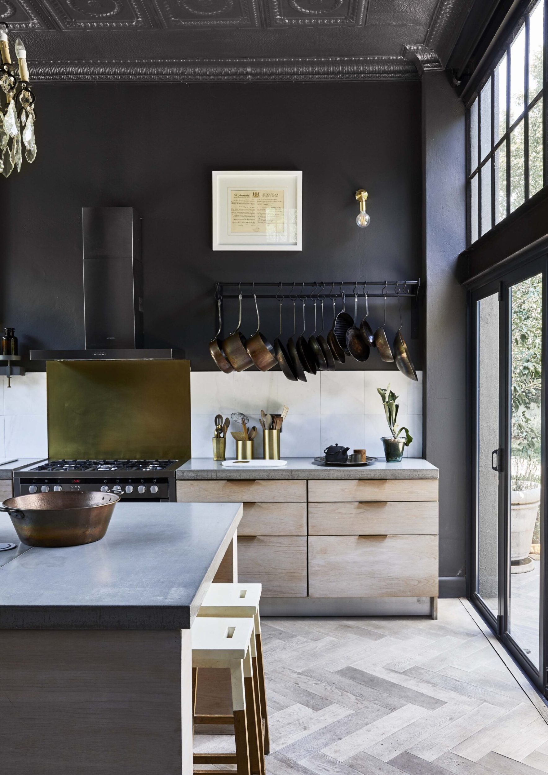 A grey tiled kitchen with wooden drawers and black walls 
