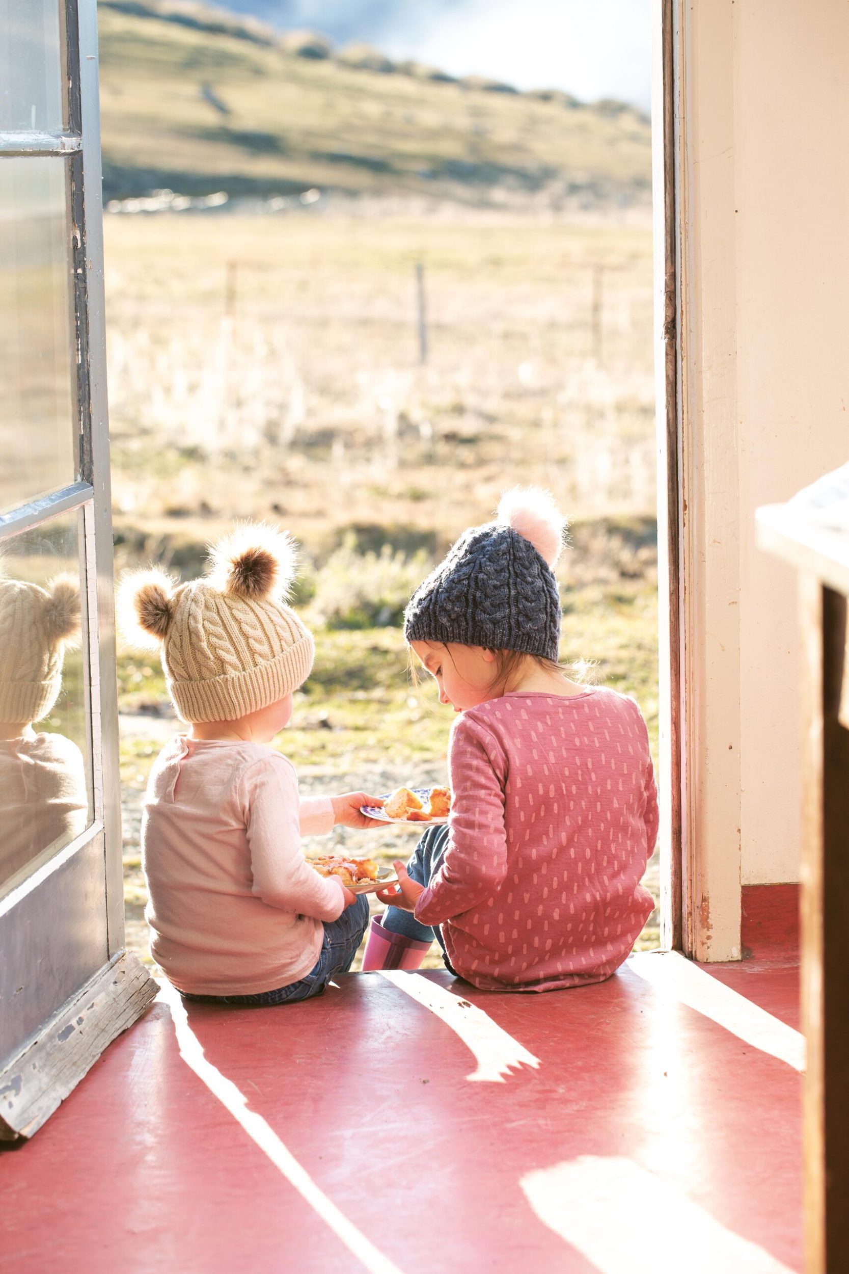 Two young girls sitting in the doorway of Otematata Station in North Otago