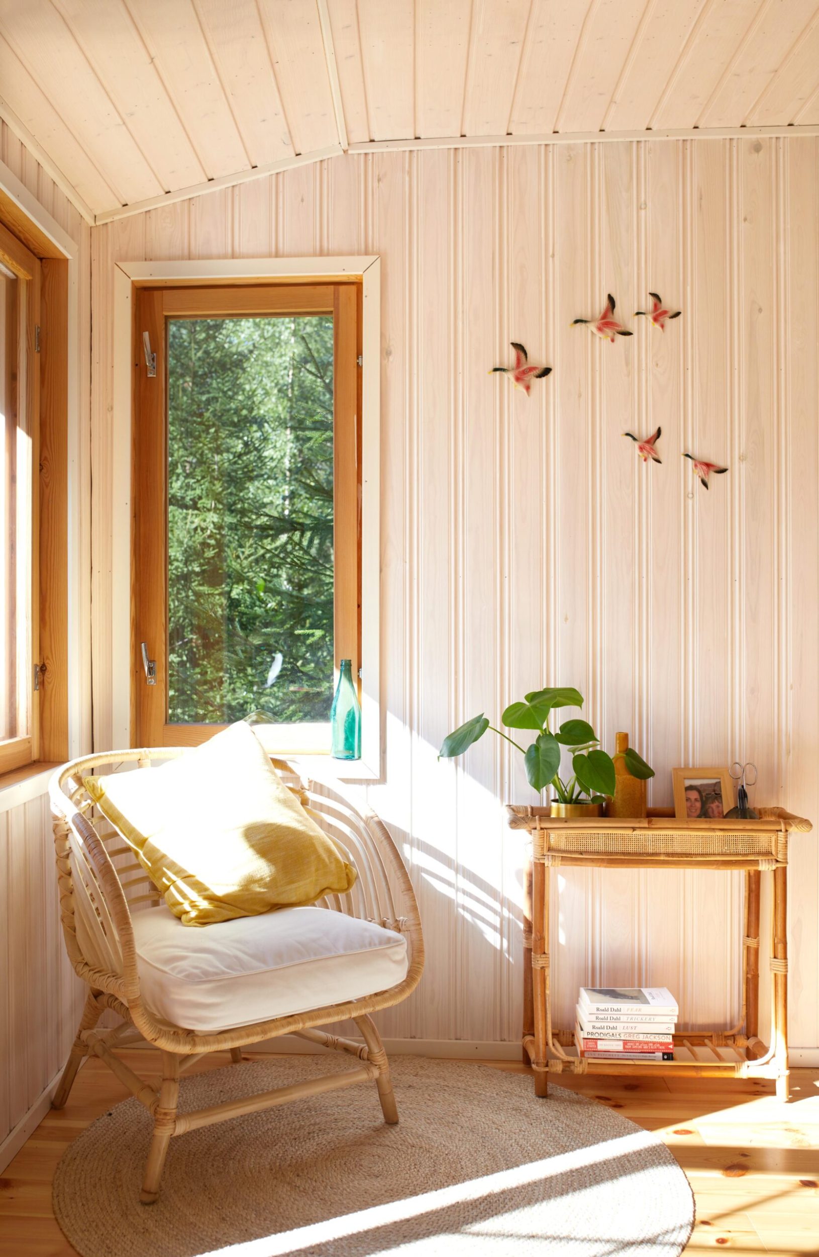 A rattan chair with white cushions in a light wood panelled room corner