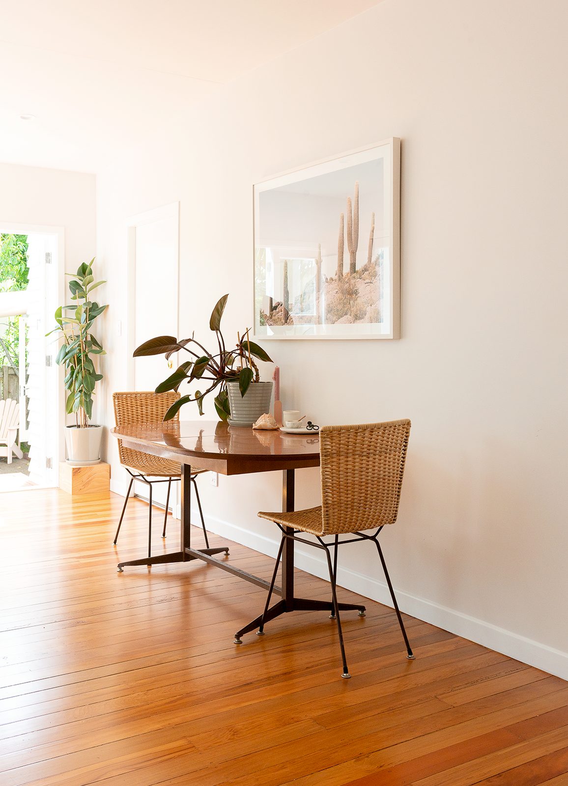 An open-plan dining area with polished wooden floors, wood tables and chairs and hanging artwork of Joshua Tree