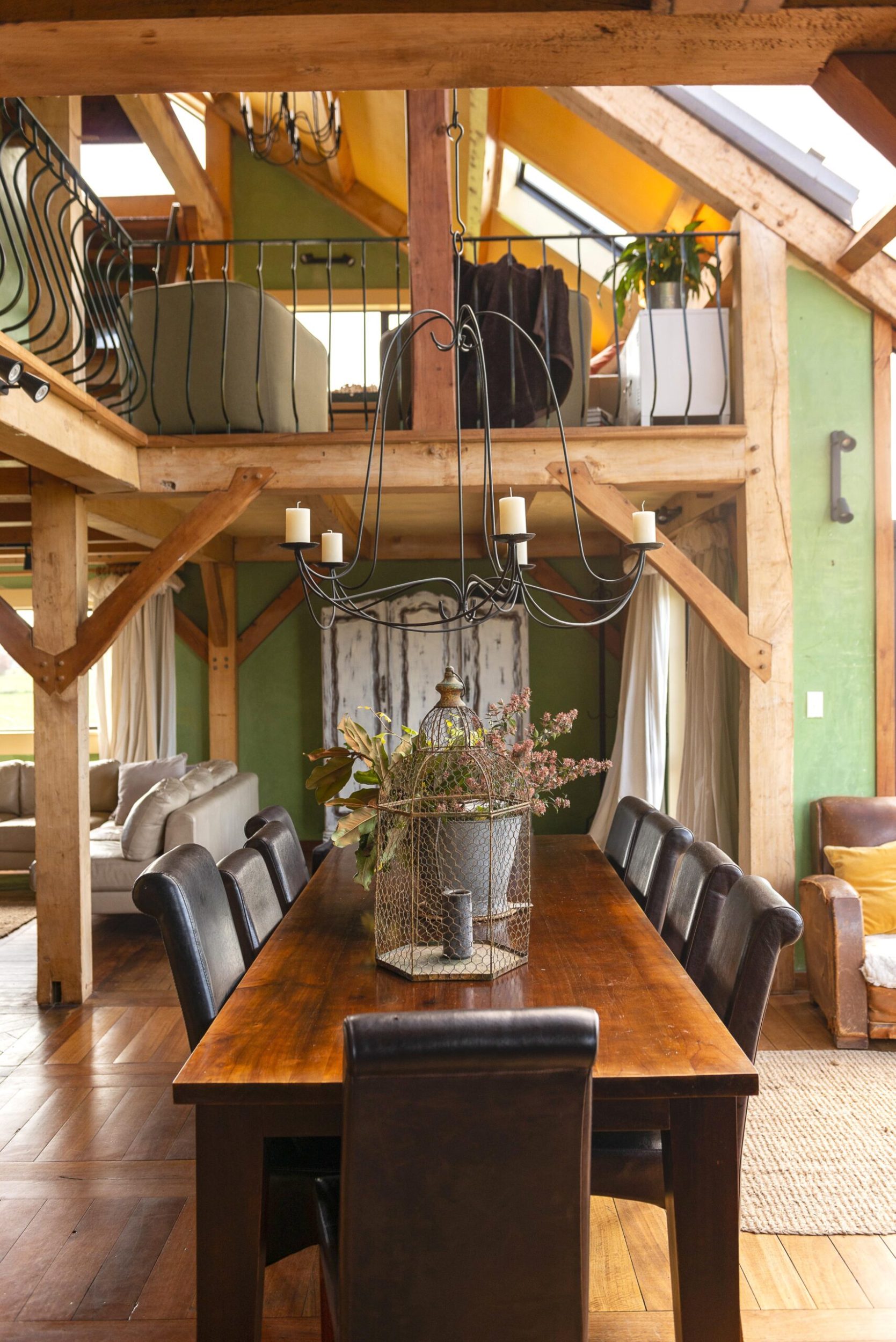 A dining room with limewashed green walls and ceiling beams in a traditional Welsh style cottage