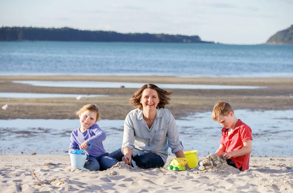 Dr Shari Gallop sitting on sand by estuary with her children