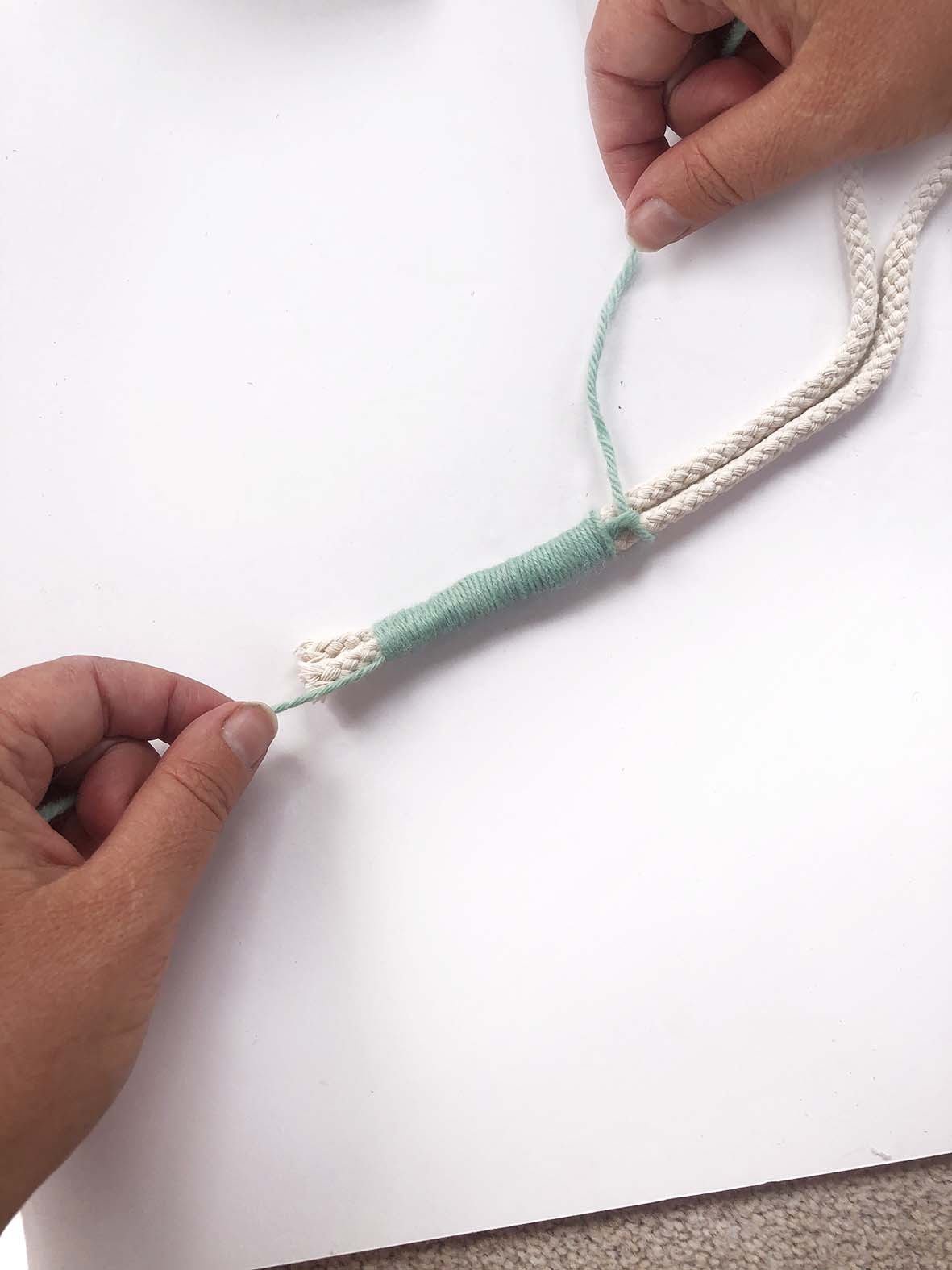 Hands wrapping wool around a cord