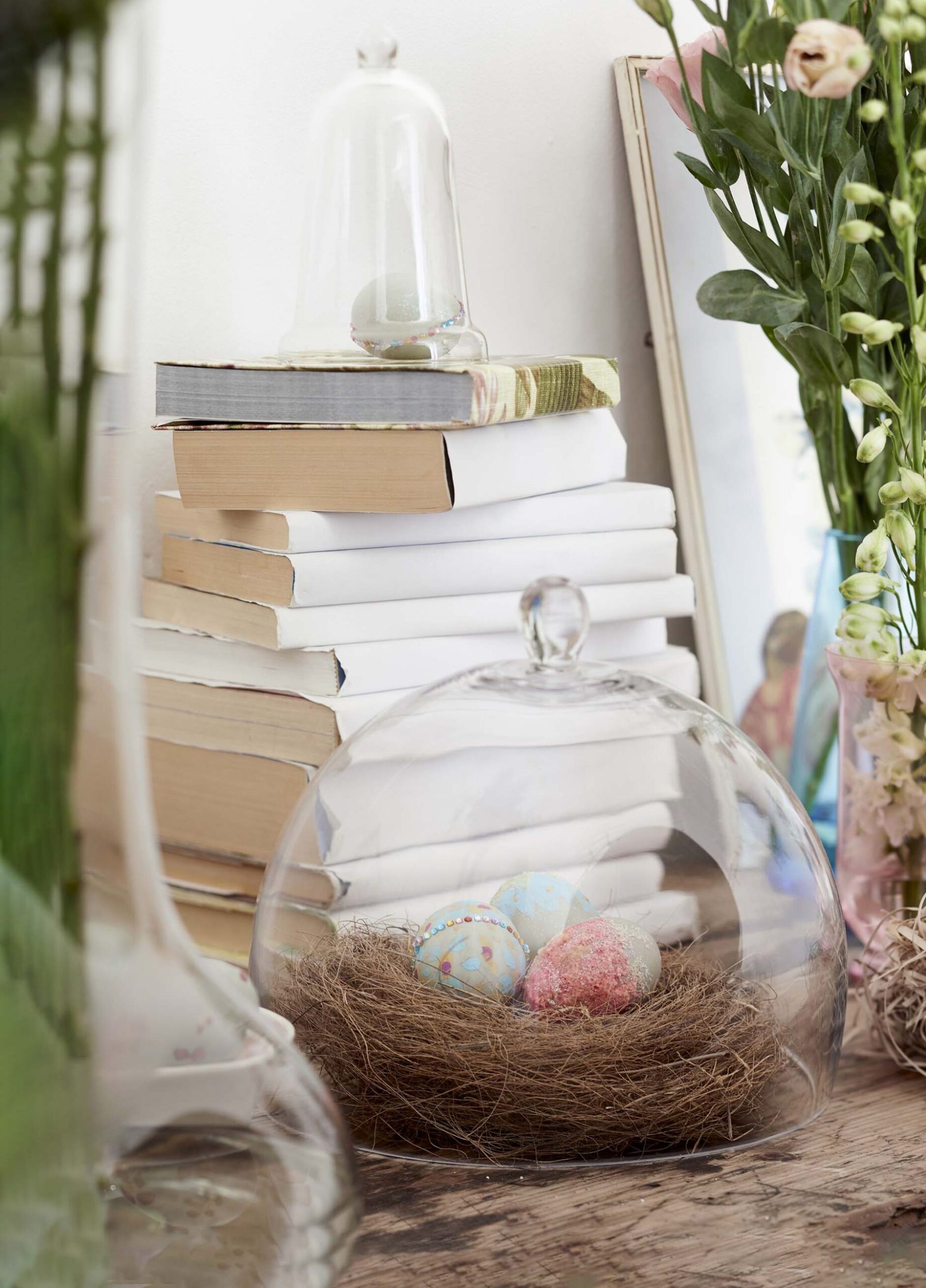 Birds nest filled with decorated easter eggs under a glass cover