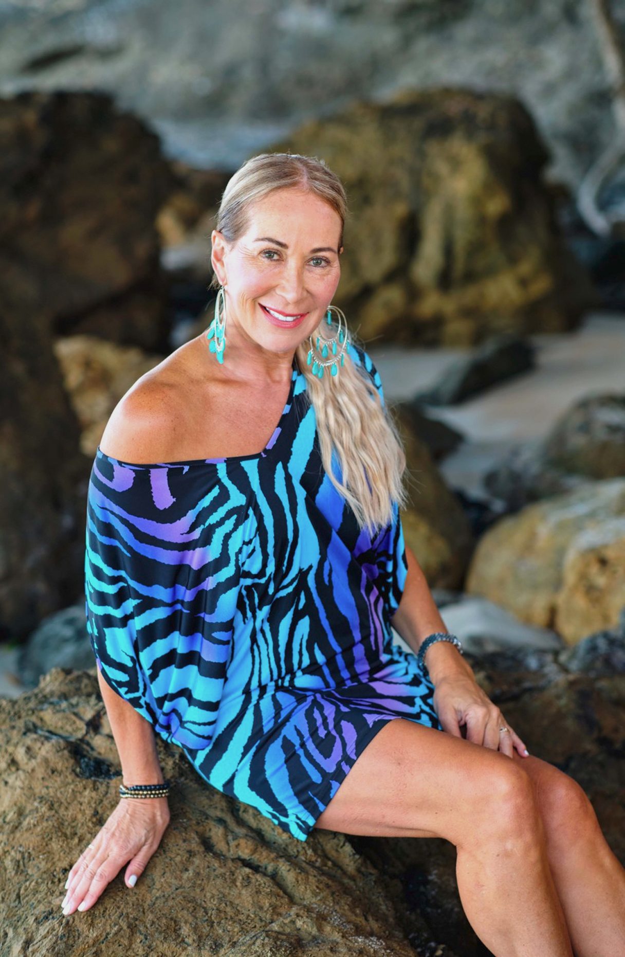 Candy Lane in a vibrant dress sitting on a rock