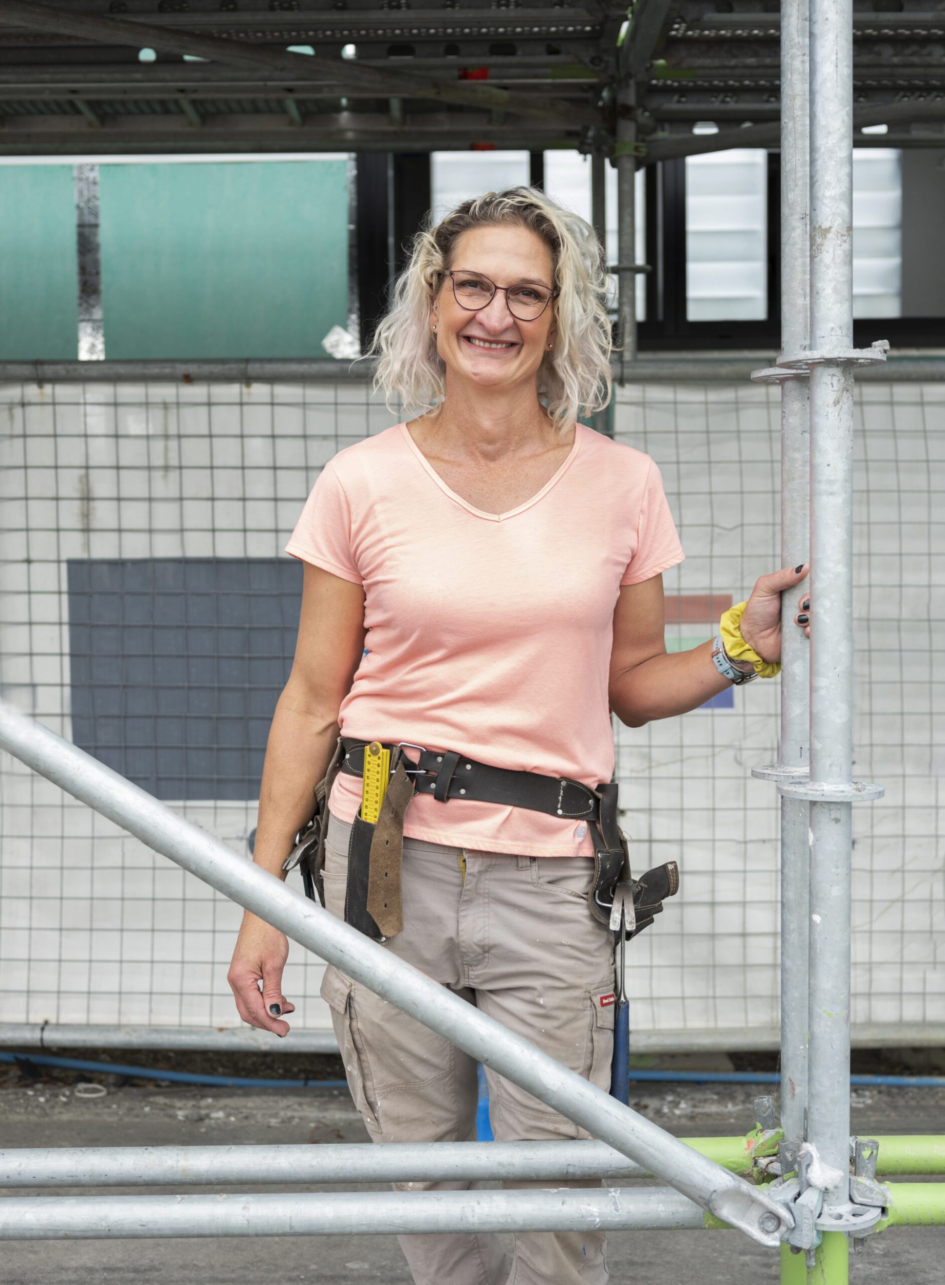 Emma Brown smiling while standing at construction site wearing tool belt