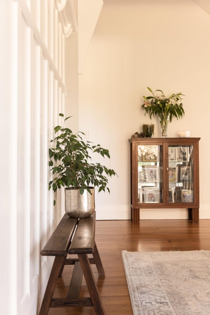 An entryway of a farmhouse home with a vintage French bench seat