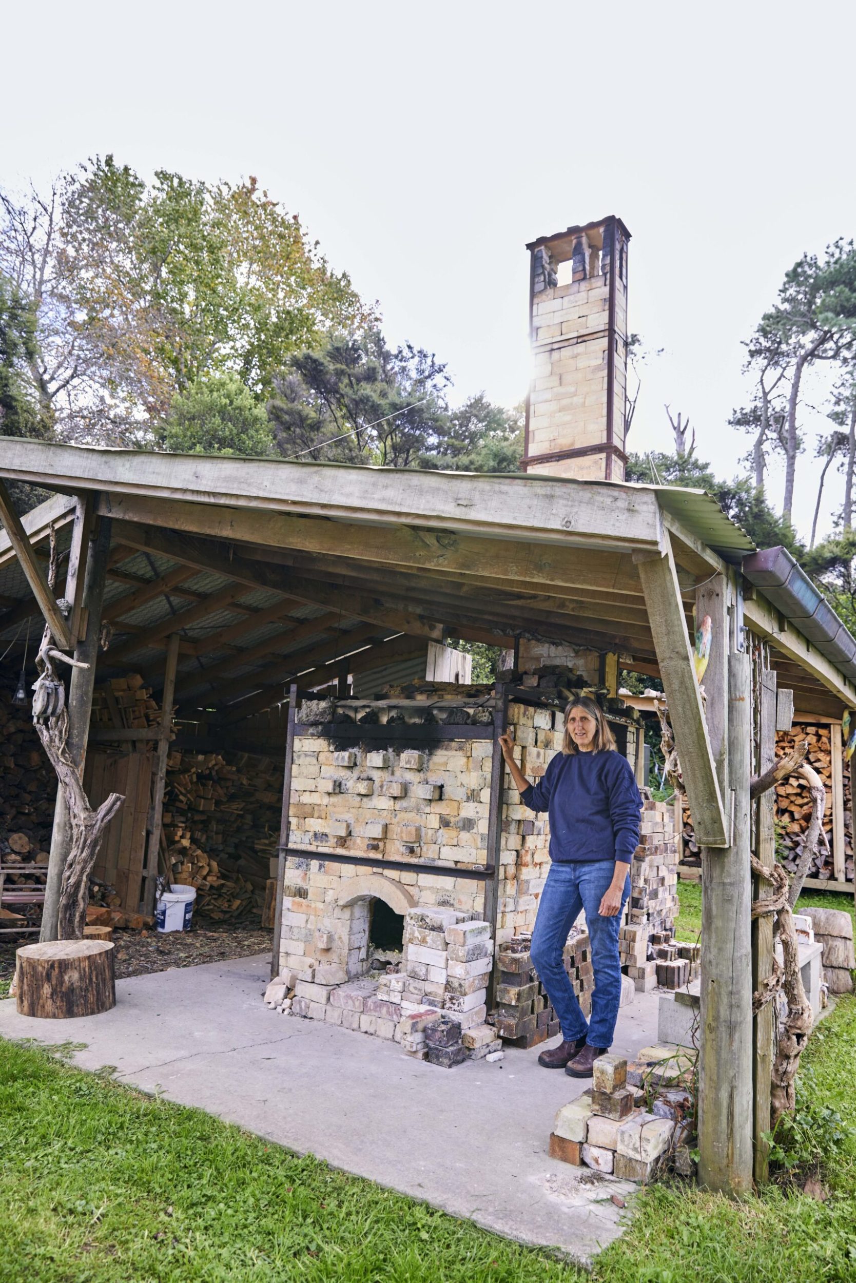 Elena Renker standing outside an outdoor kiln
