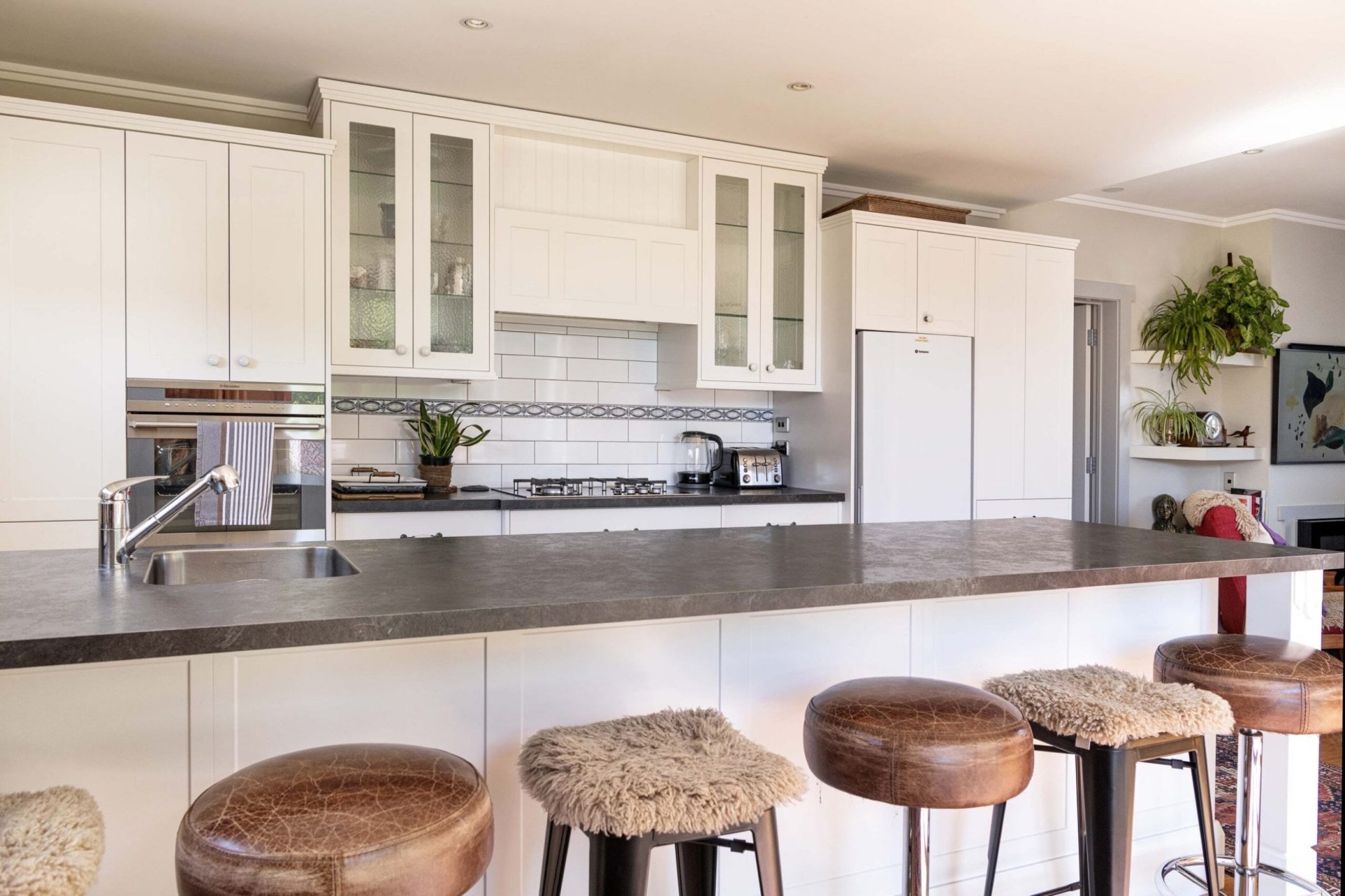 A kitchen with brown benchtops and multicoloured chairs