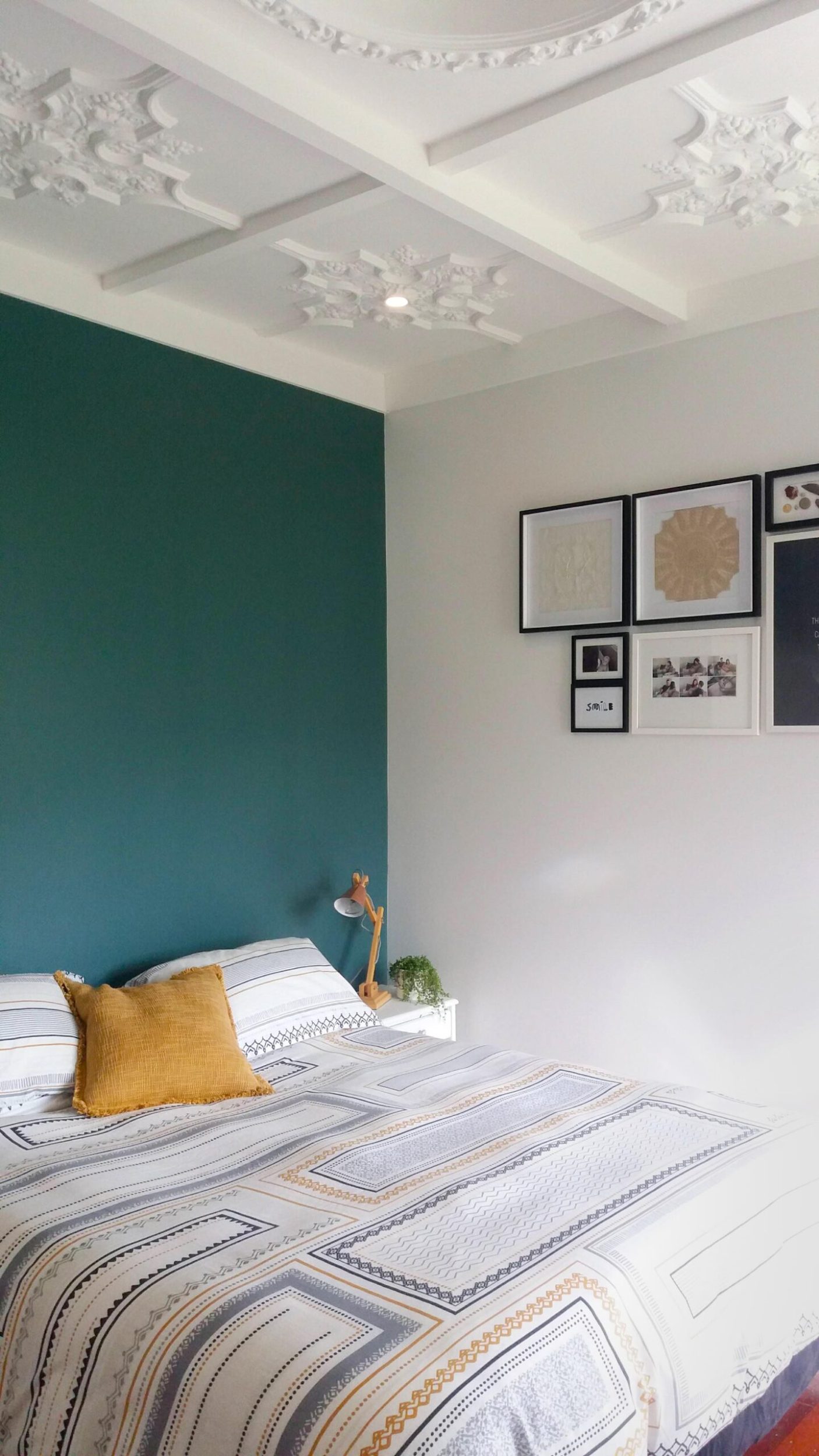 A bedroom with white and emerald green walls and a vintage period ceiling