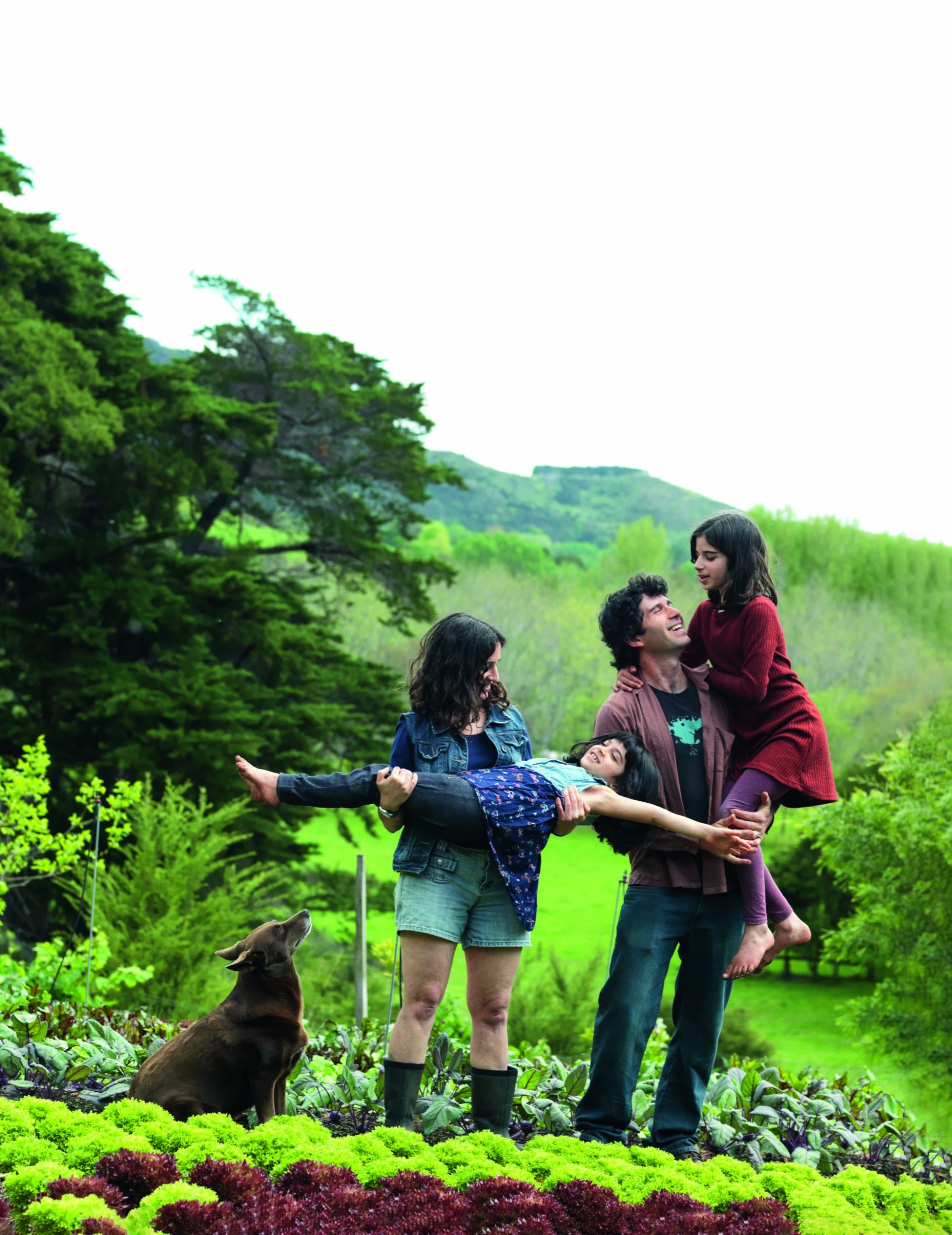 Niva and Yotam Kay holding their daughters Dina and Lily while standing in their green farm