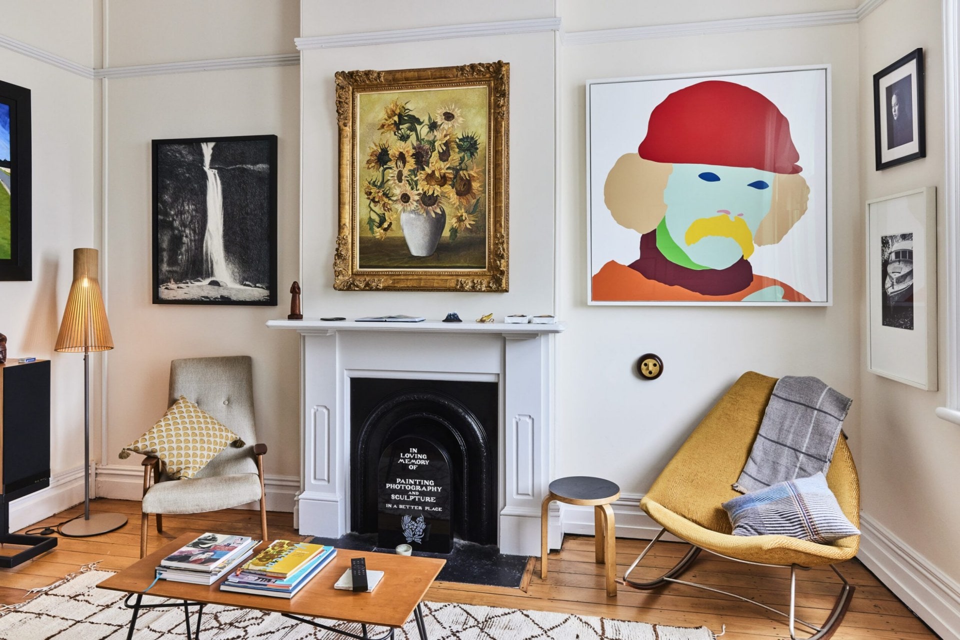 White walls and a black fireplace surrounded by assorted hanging art and black and white photography 