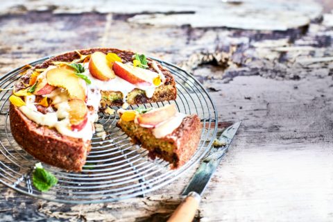Courgette and raisin cake on a wooden table surrounded by yellow flowers