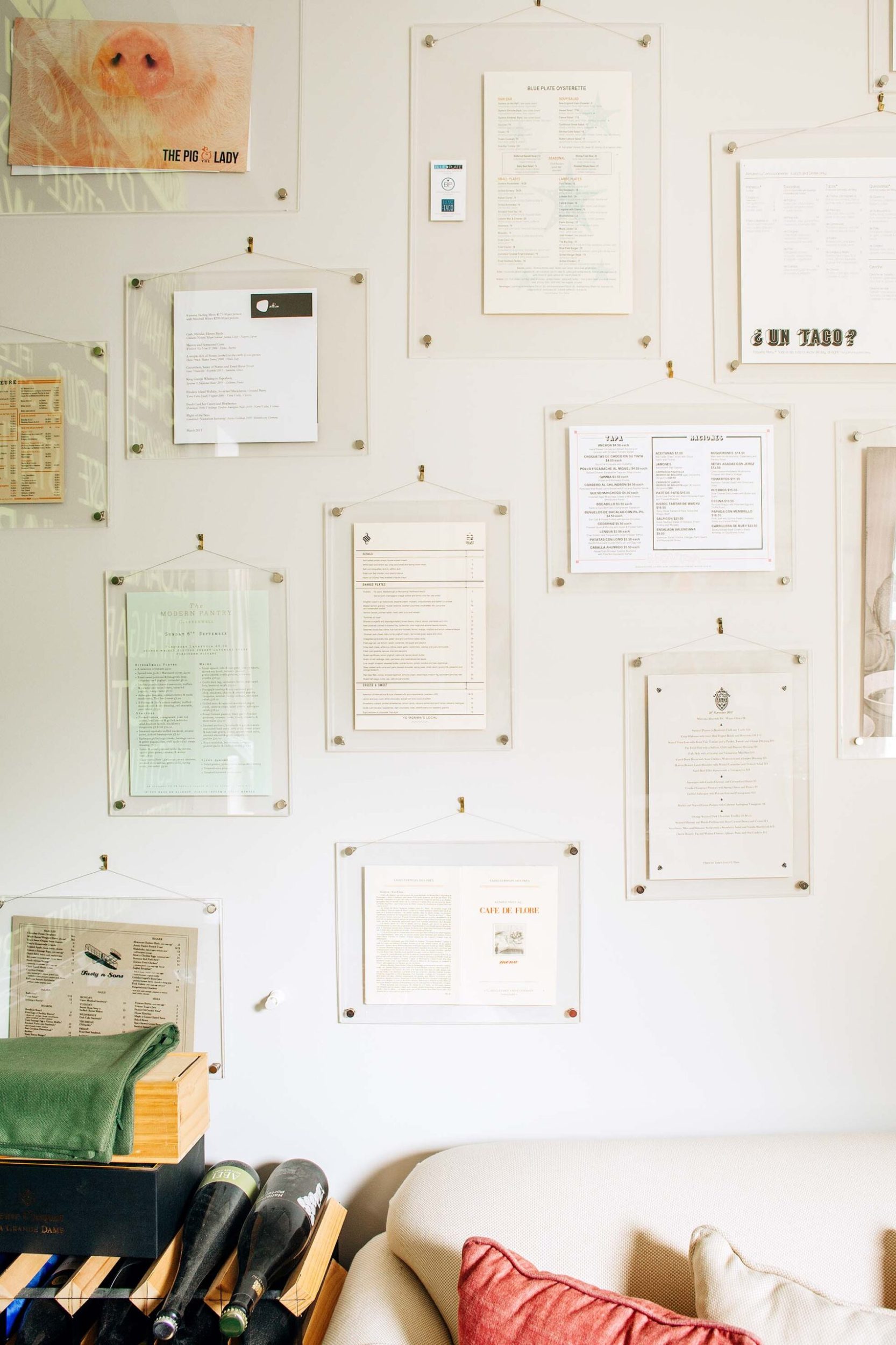 A white wall with assorted dining menus in plastic frames hanging on it