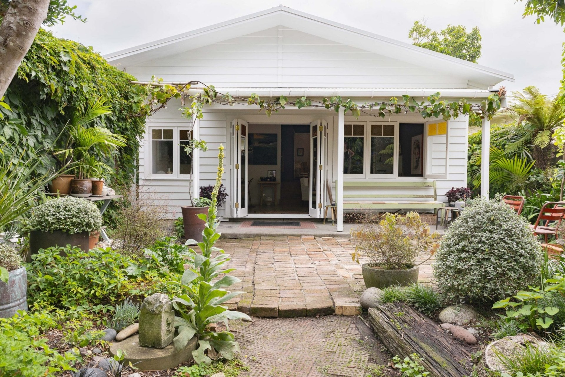 The external of a white bungalow in Pt Chev surrounded by a garden