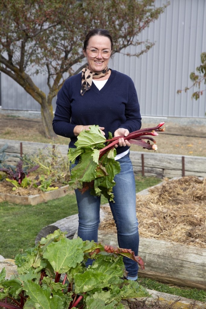 Philippa Cameron standing in a garden holding rhubarb leaves