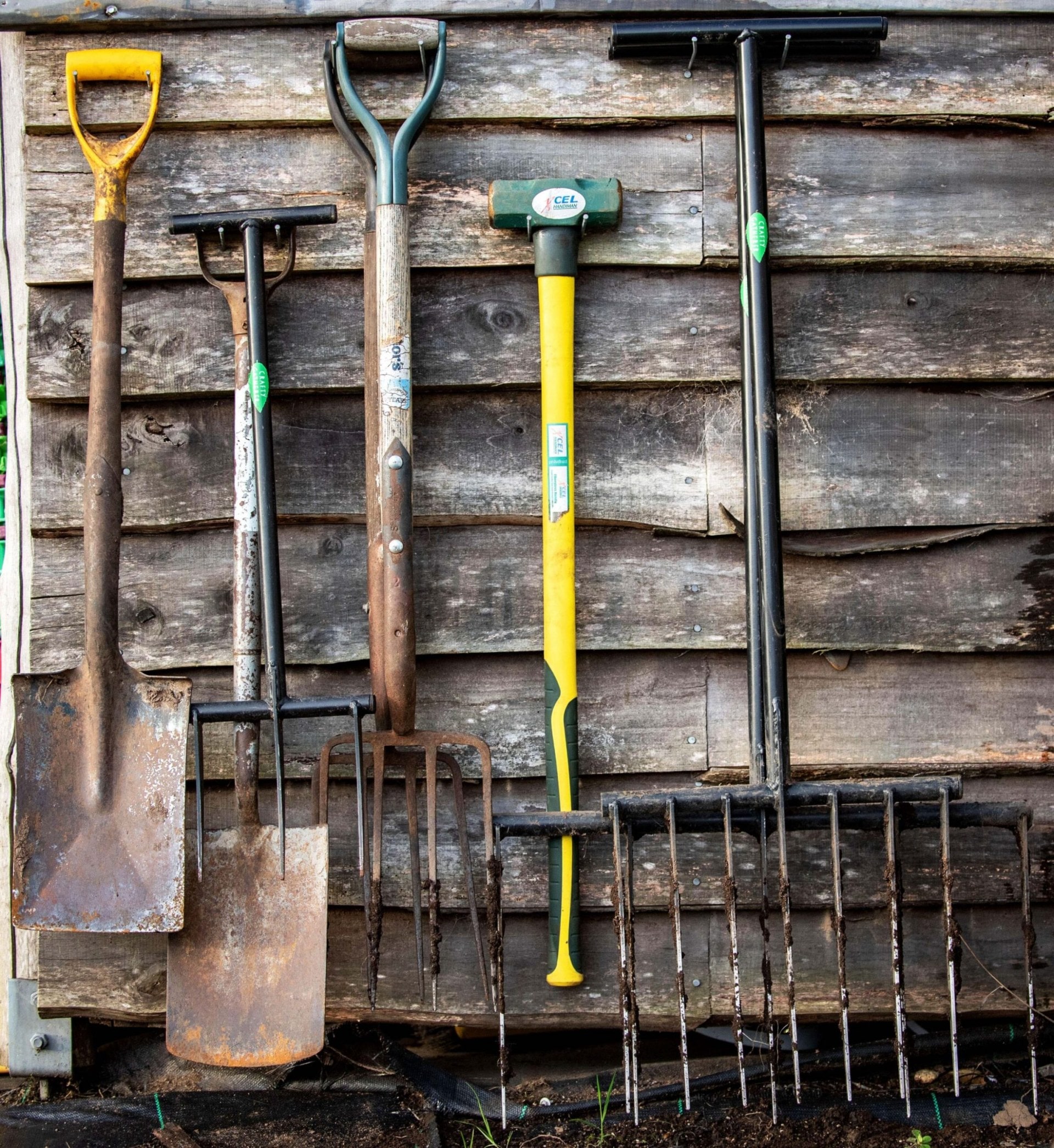 A wood shed with an assortment of garden tools hanging