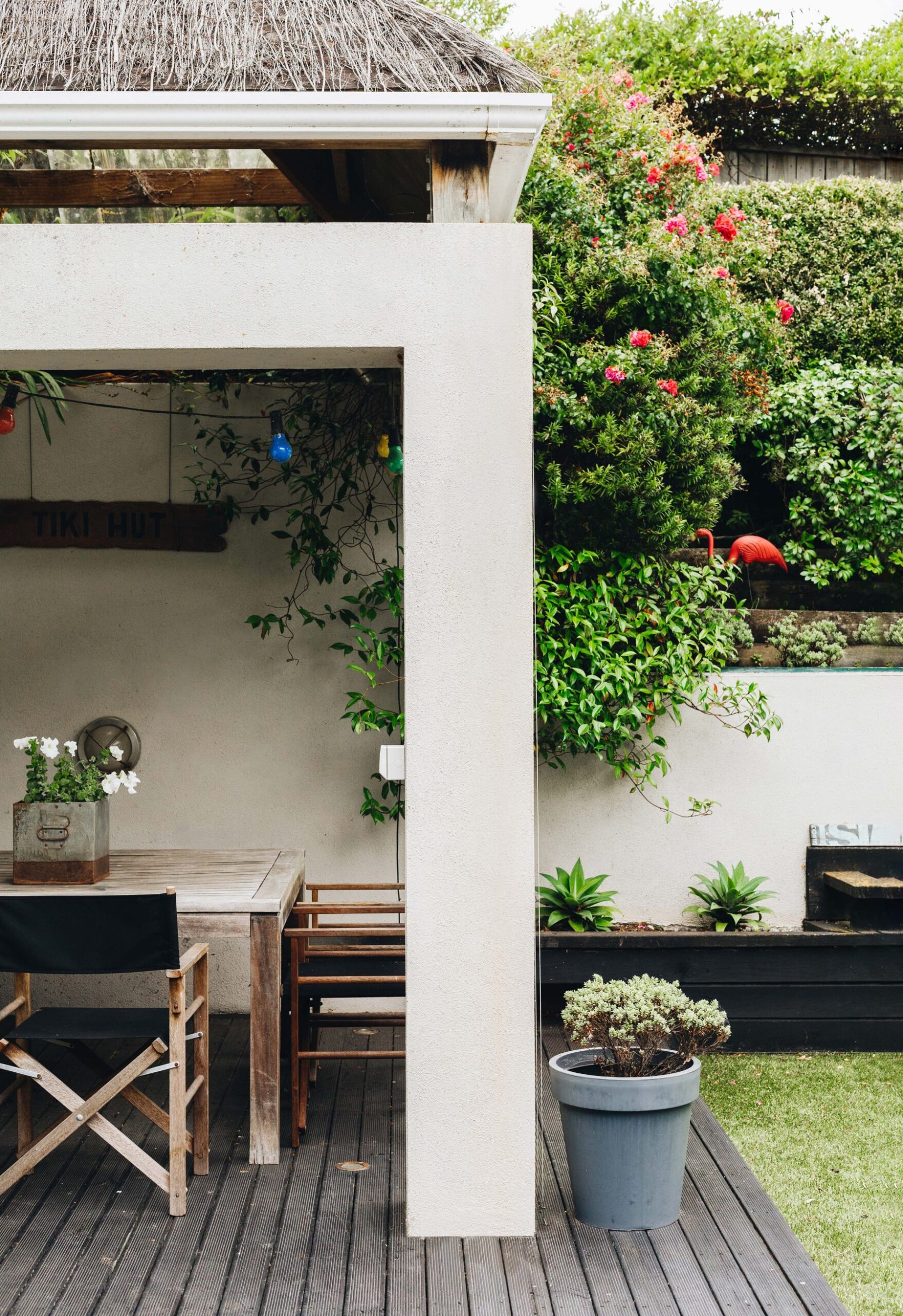 A garden with a beige gazebo and wooden outdoor dining table