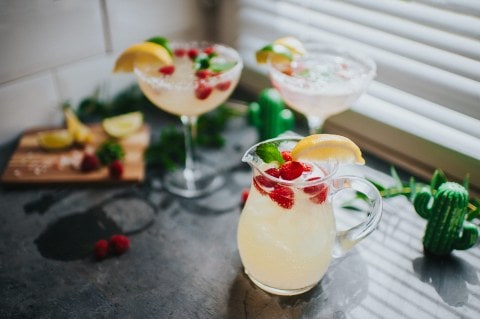 Stylishly presented margherita cocktails, in a kitchen environment with a jug, and dressed with fruit.