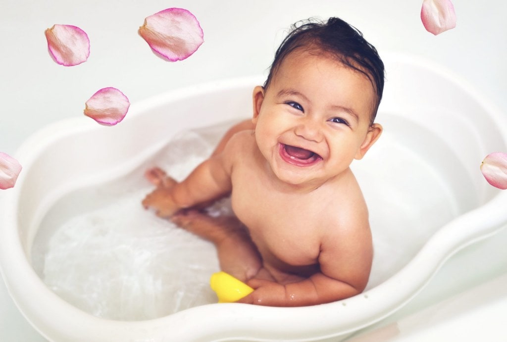 Baby in a bath surrounded by pink petals