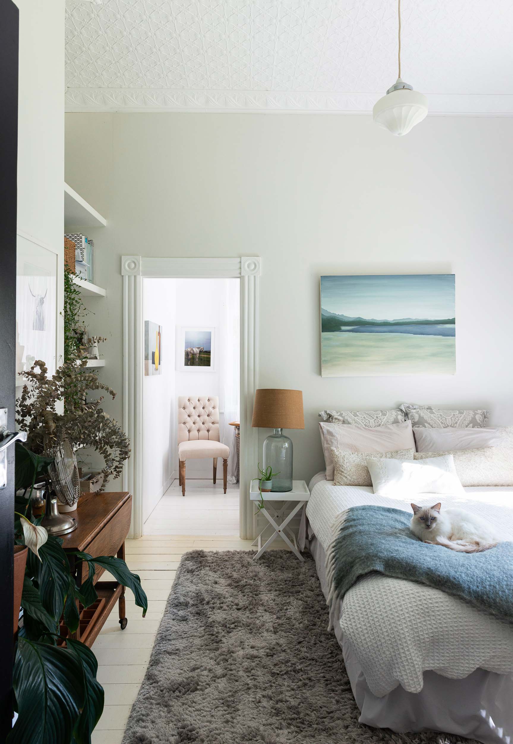 A bedroom with a blue theme, the bed has white and blue linen, a shaggy grey rug is on the floor.