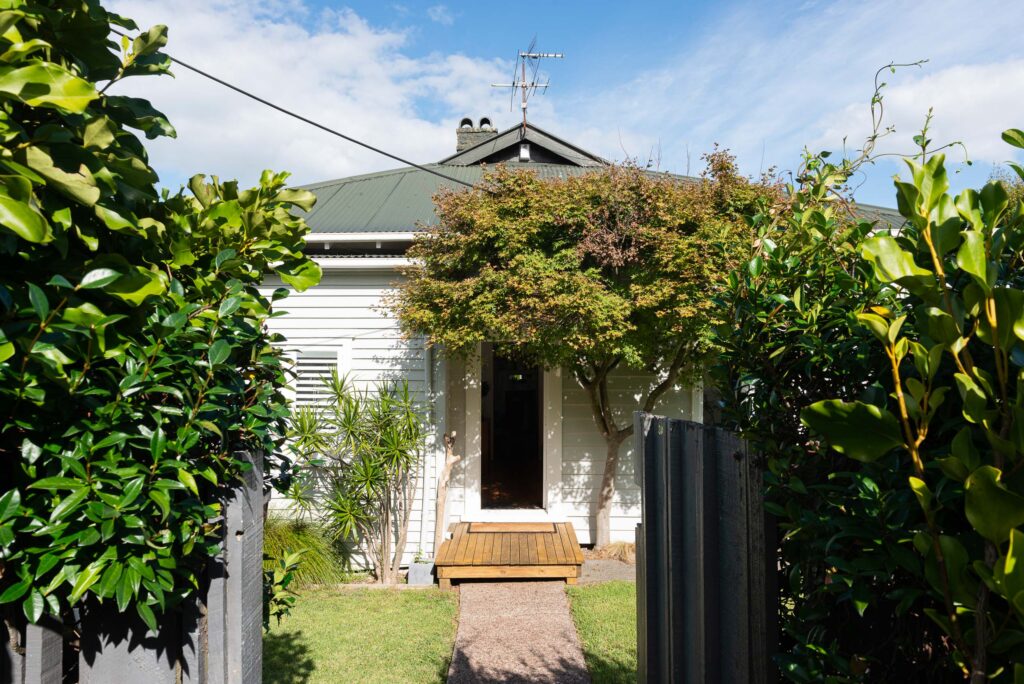 A little villa with a deck to the door and a tree framing the door