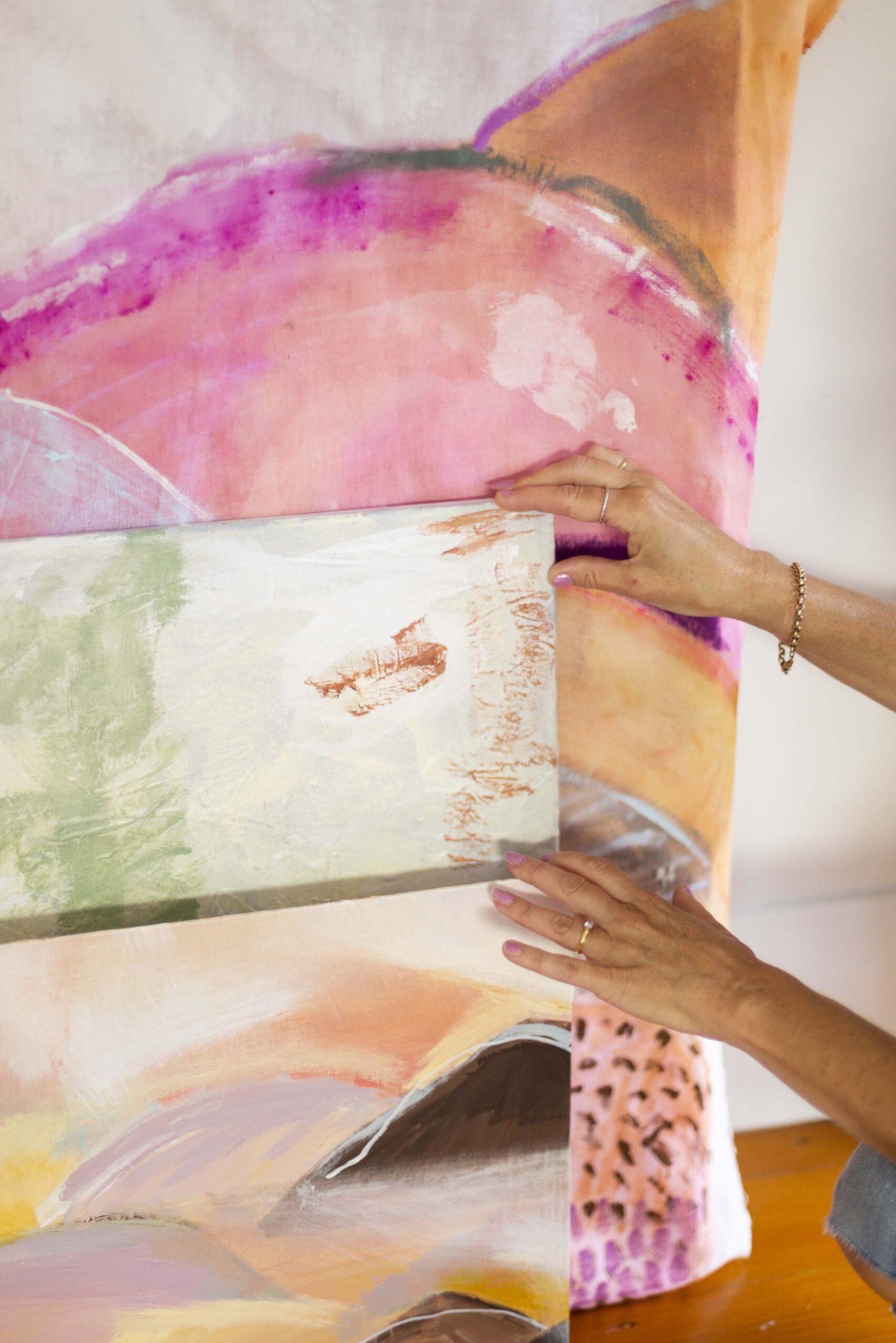 Brenda Clews holding assorted artworks leaning against wall