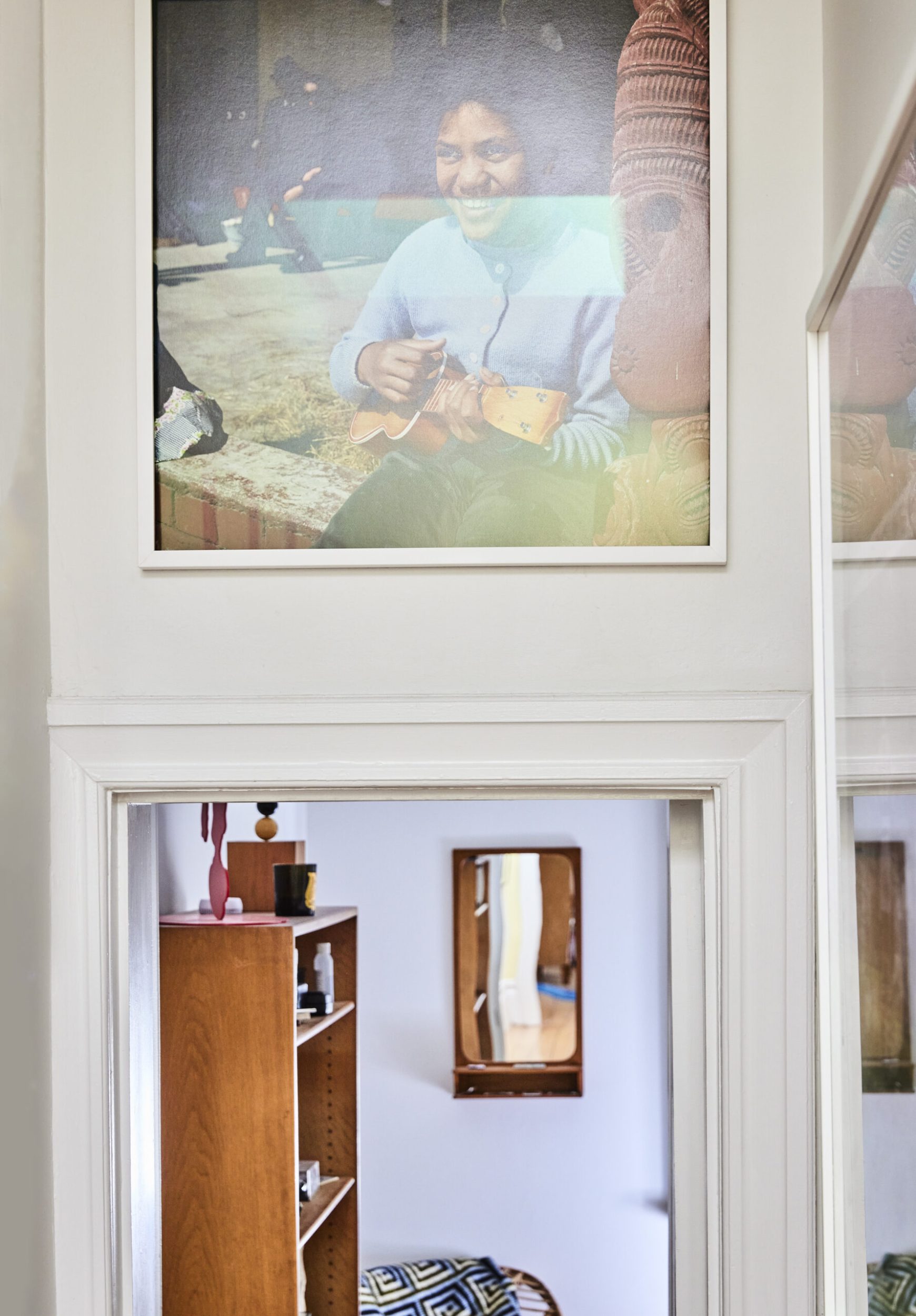 A hanging framed photograph of a girl smiling while playing guitar hanging above open door