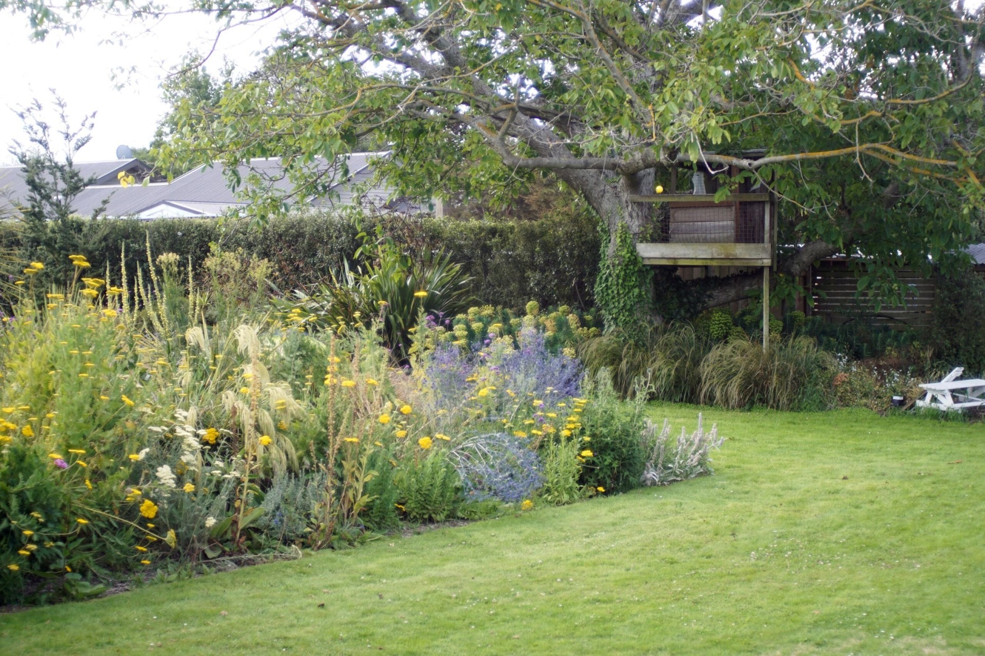 A treehouse sitting in a full garden.