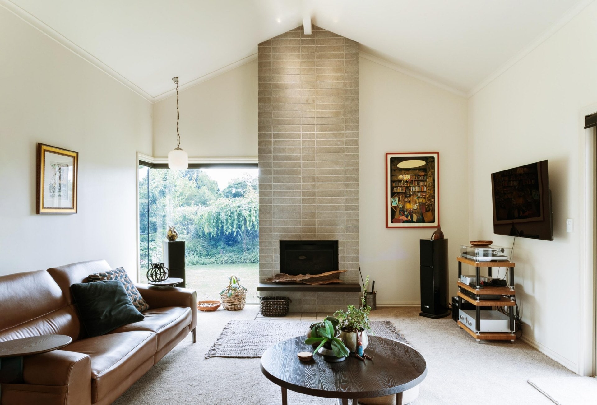 Lynda Wilson's lounge room, with a brick feature leading up to the pitched ceiling and a leather couch to the left