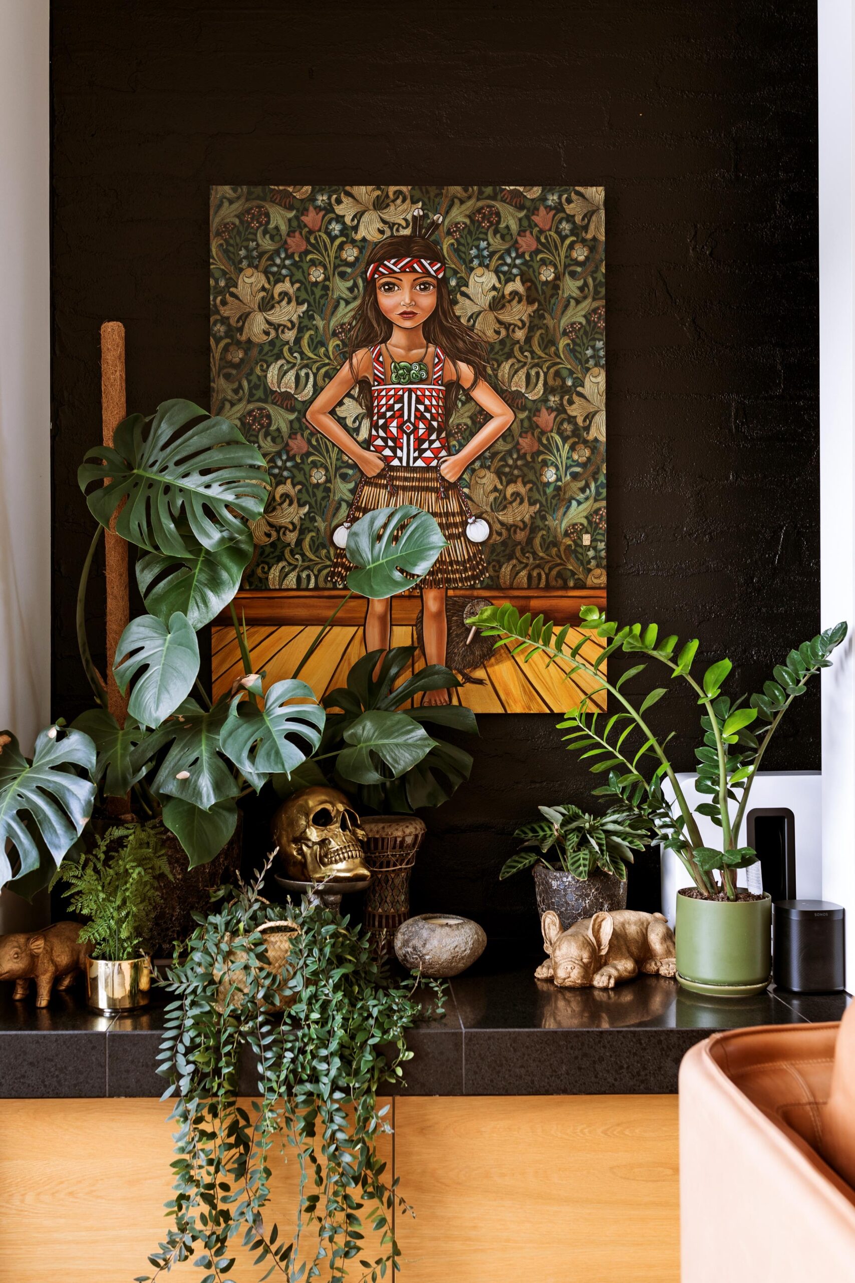 A painting of a Maori girl sits atop a plant-covered bench.