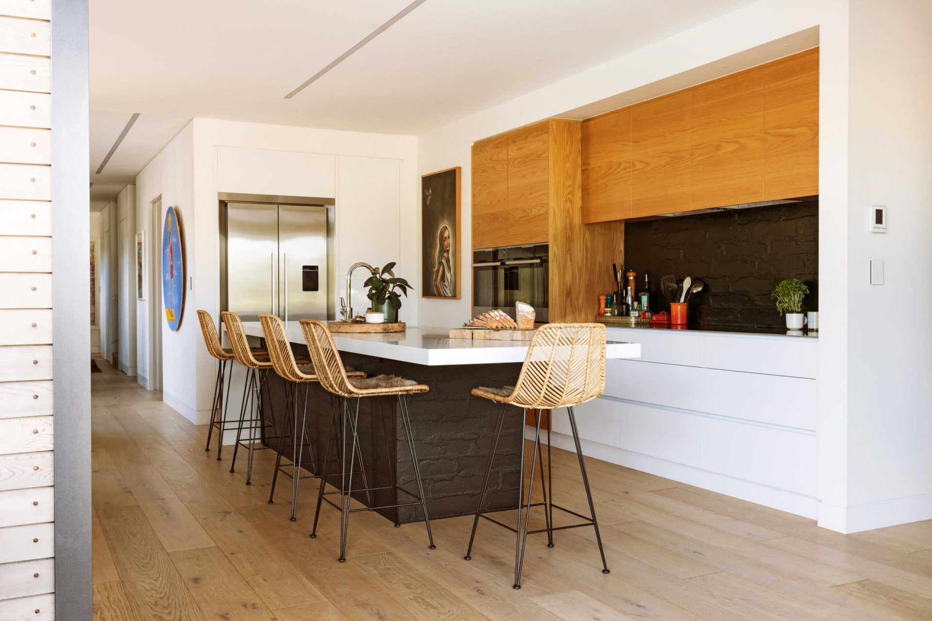 Sunny kitchen area with bar stools around a bench.