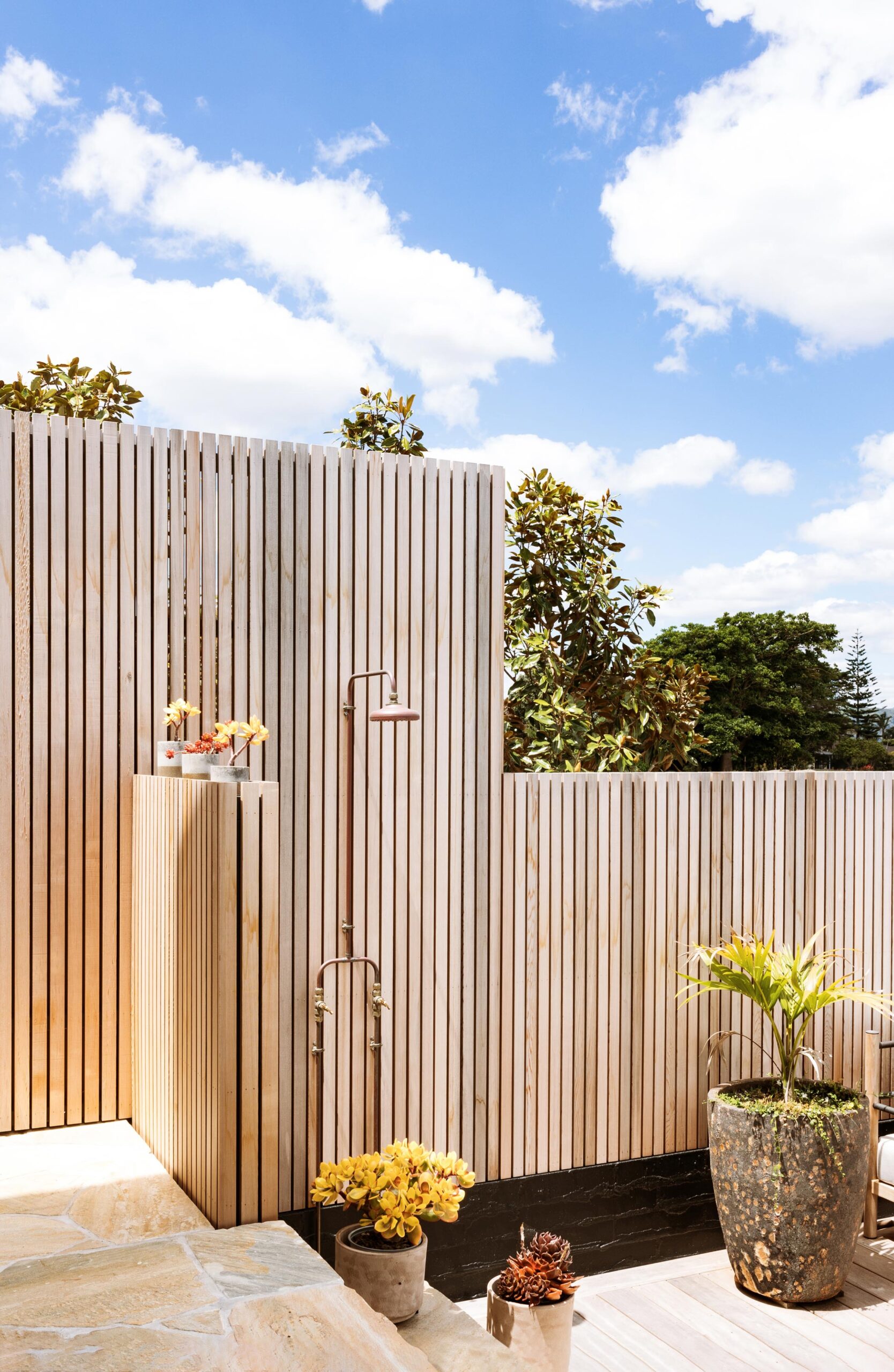 Wooden outdoor wall with shower and plants.