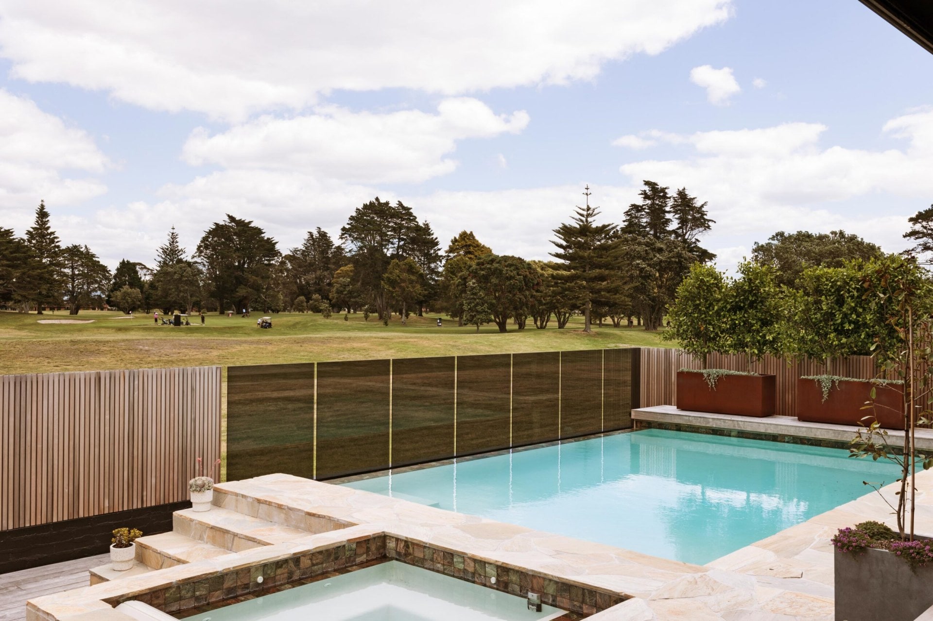 Outdoor pool with golf course over the fence.