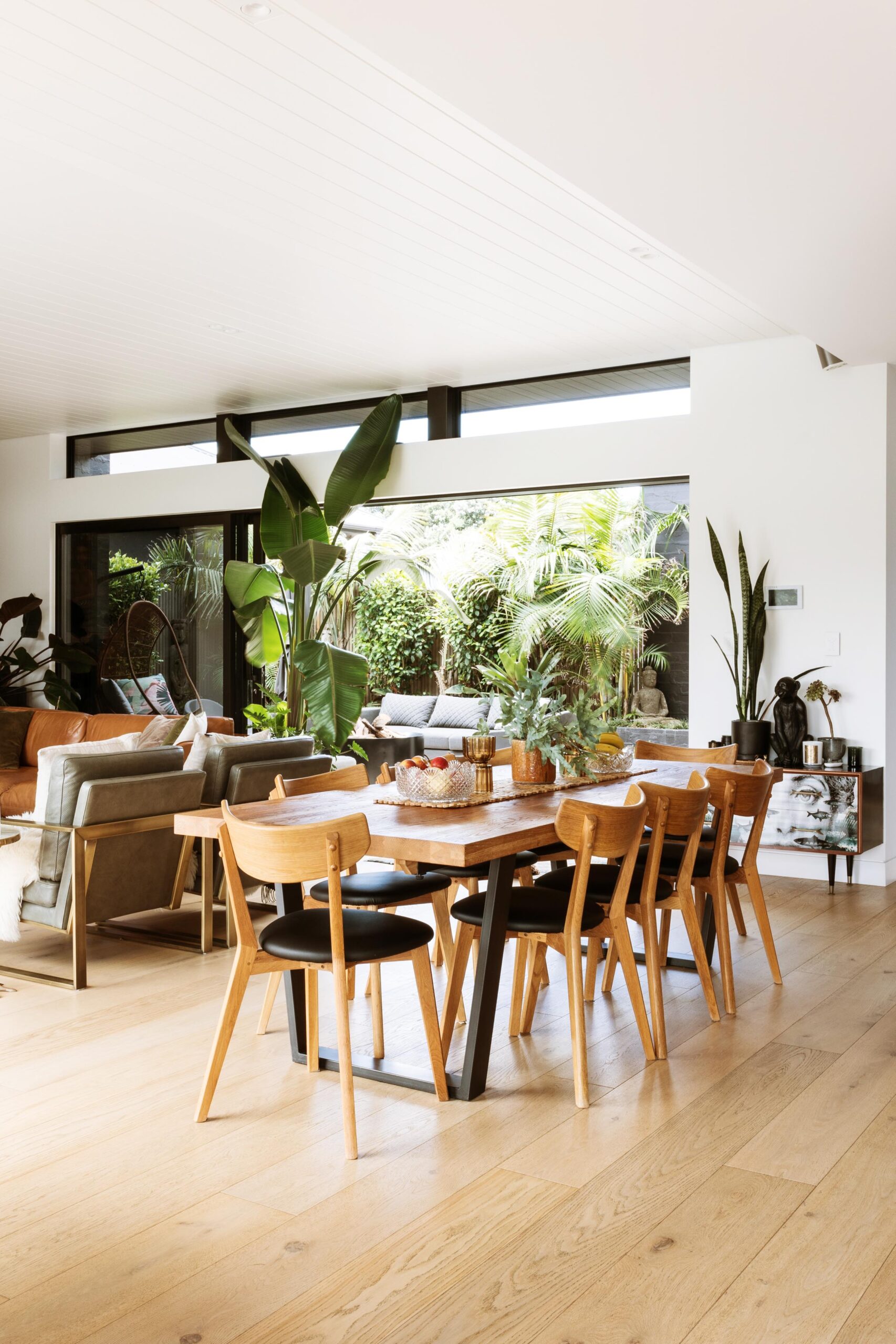 A wooden dining table and chairs with a plant centerpiece.