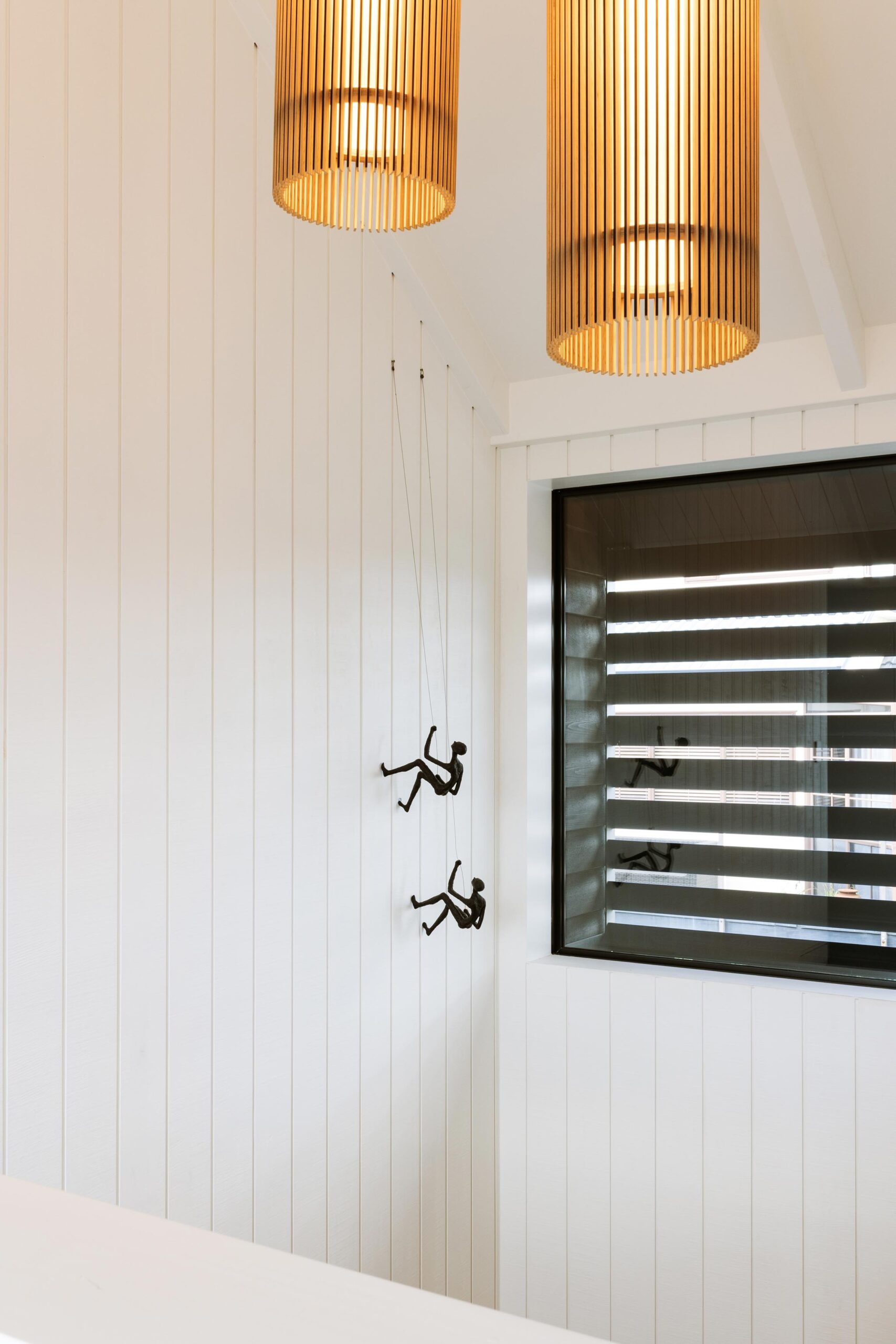 A white wooden panelled wall with hanging pendant lights.