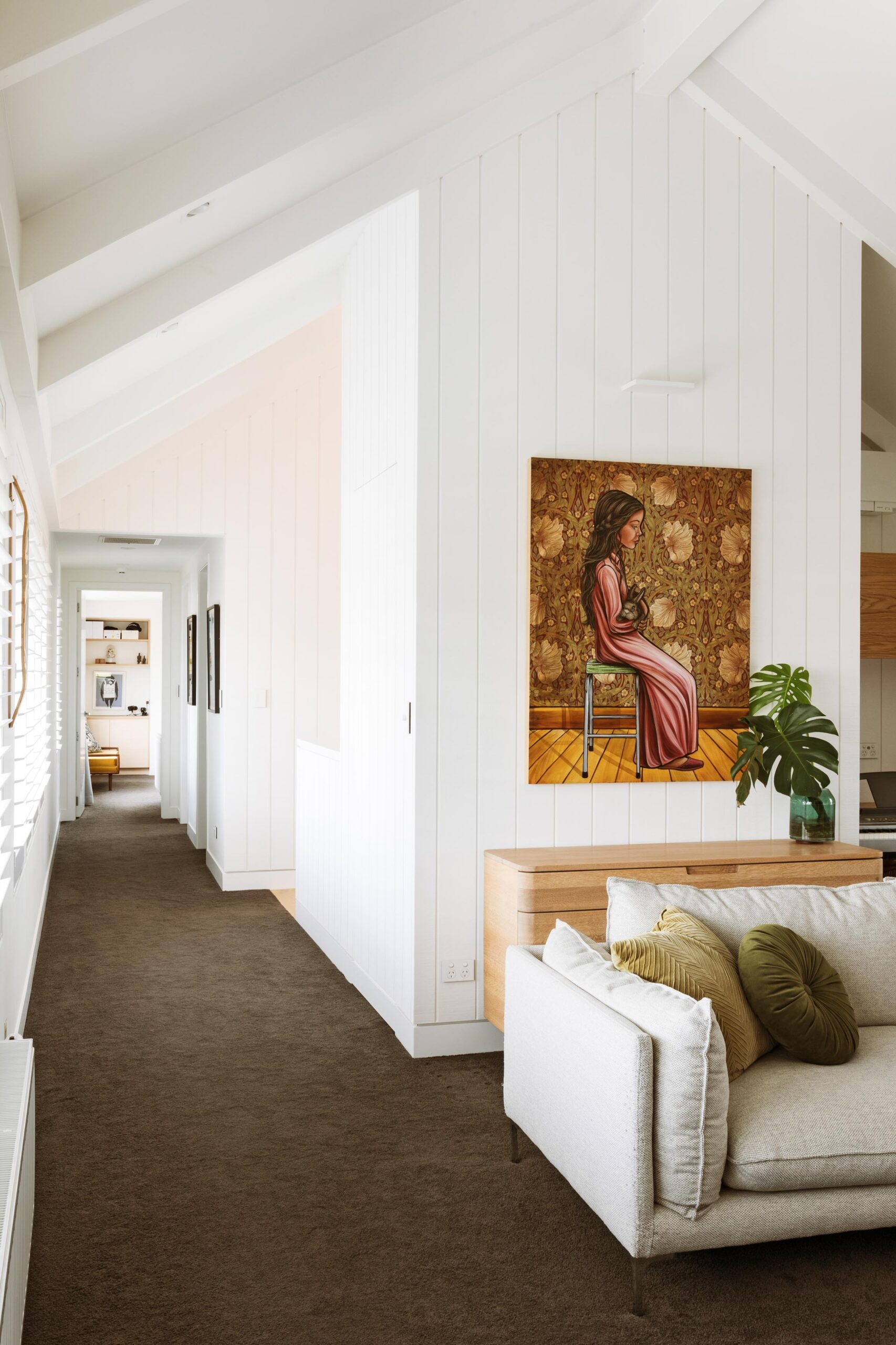 A sunny hallway with grey couch.