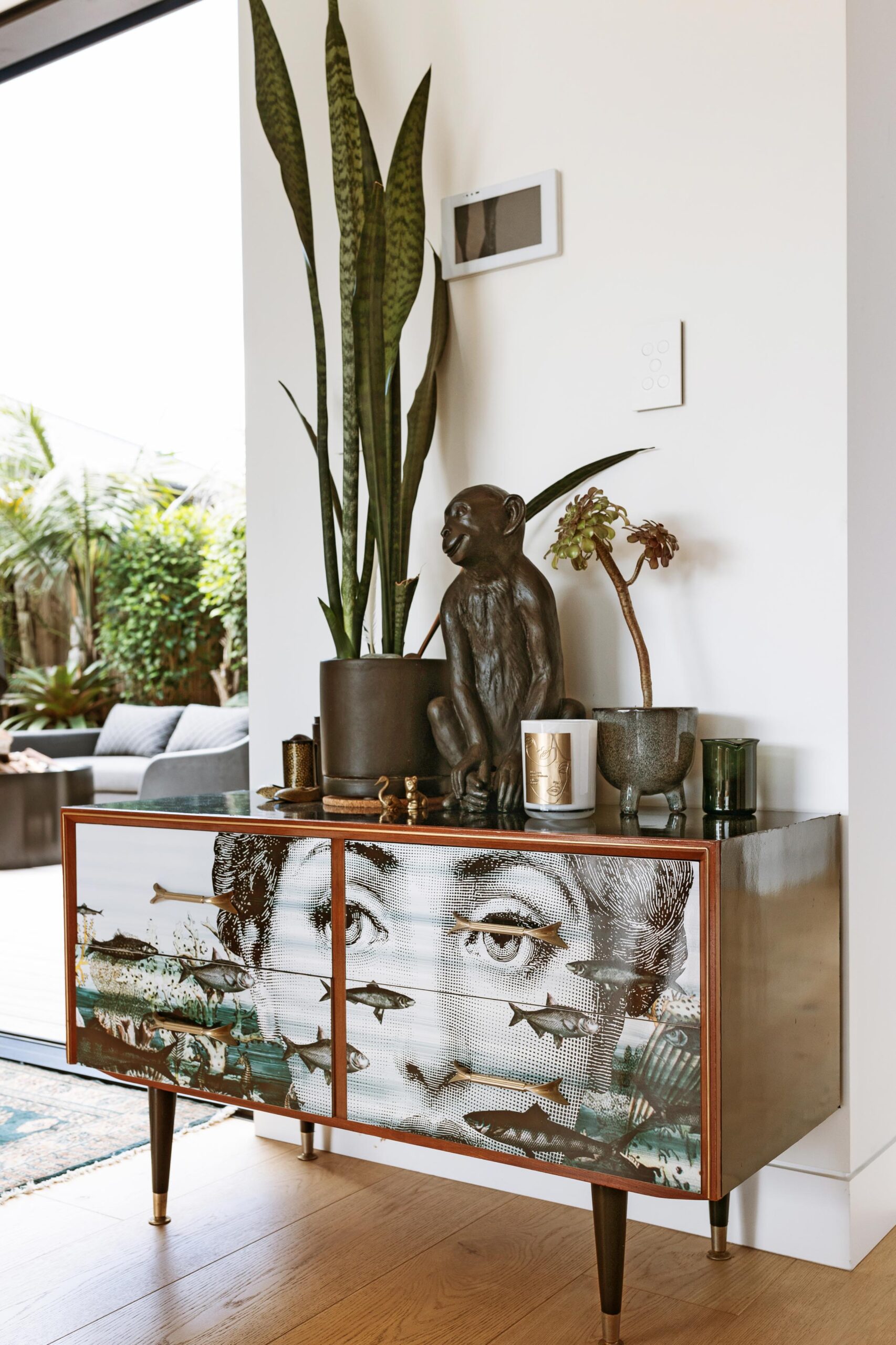 Plants and art sitting on top of a vintage sideboard.