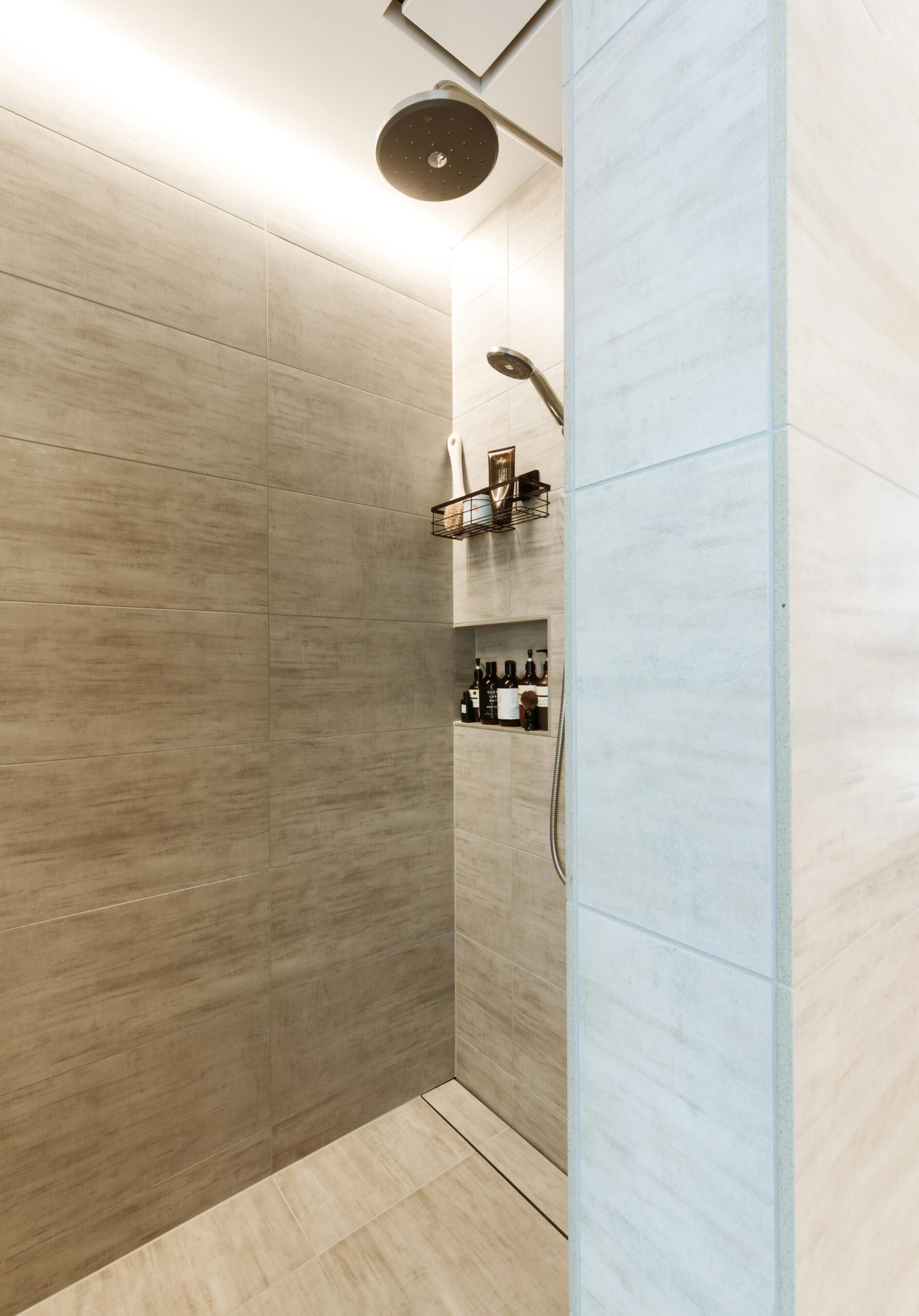 A neutral-toned shower with products on shelves.