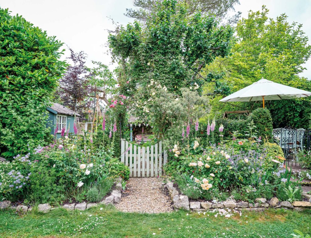 a sprawling garden with small grey gate on a leafy path