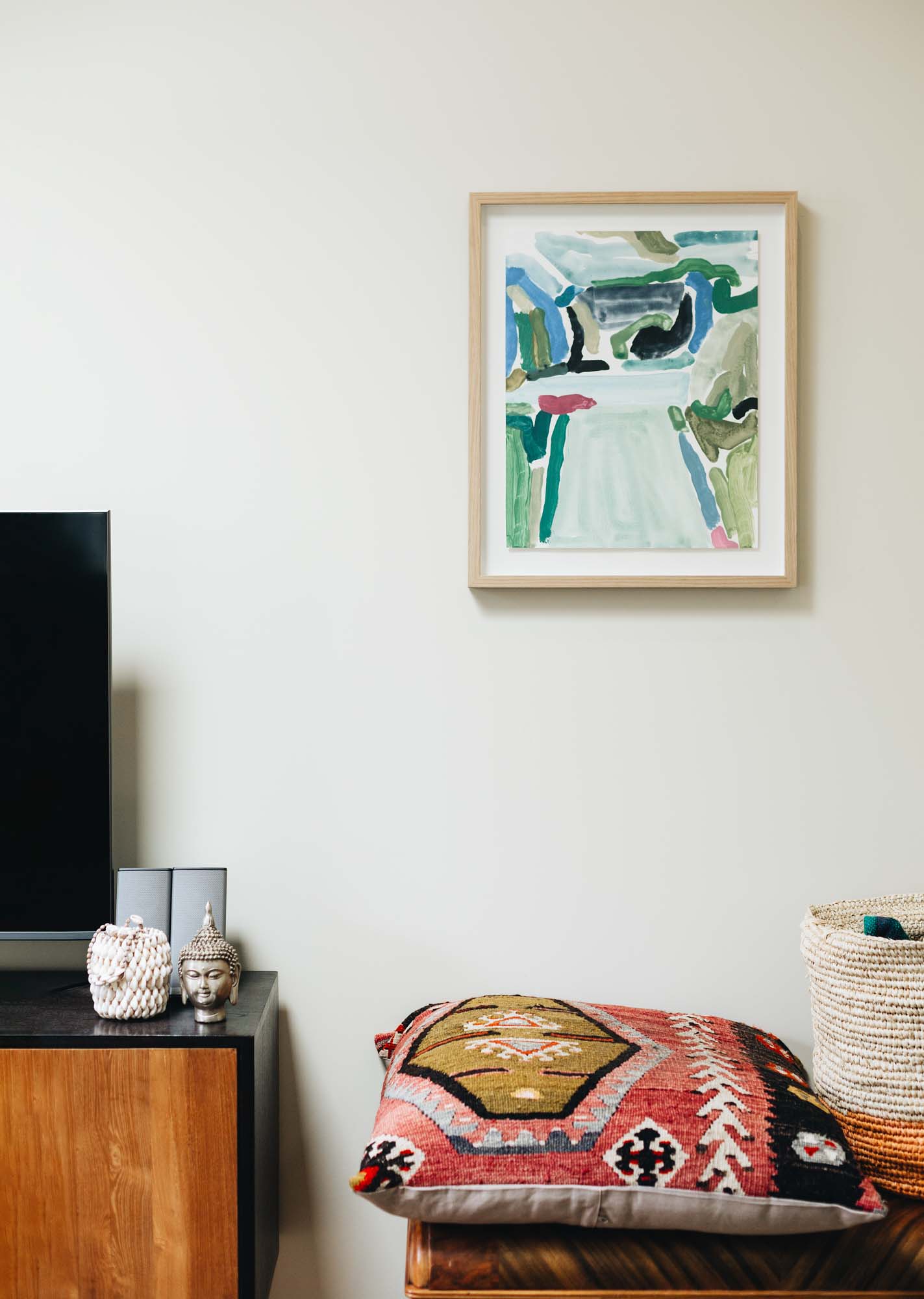 Coloured cushions sit on a unit, and a blue painting on the wall