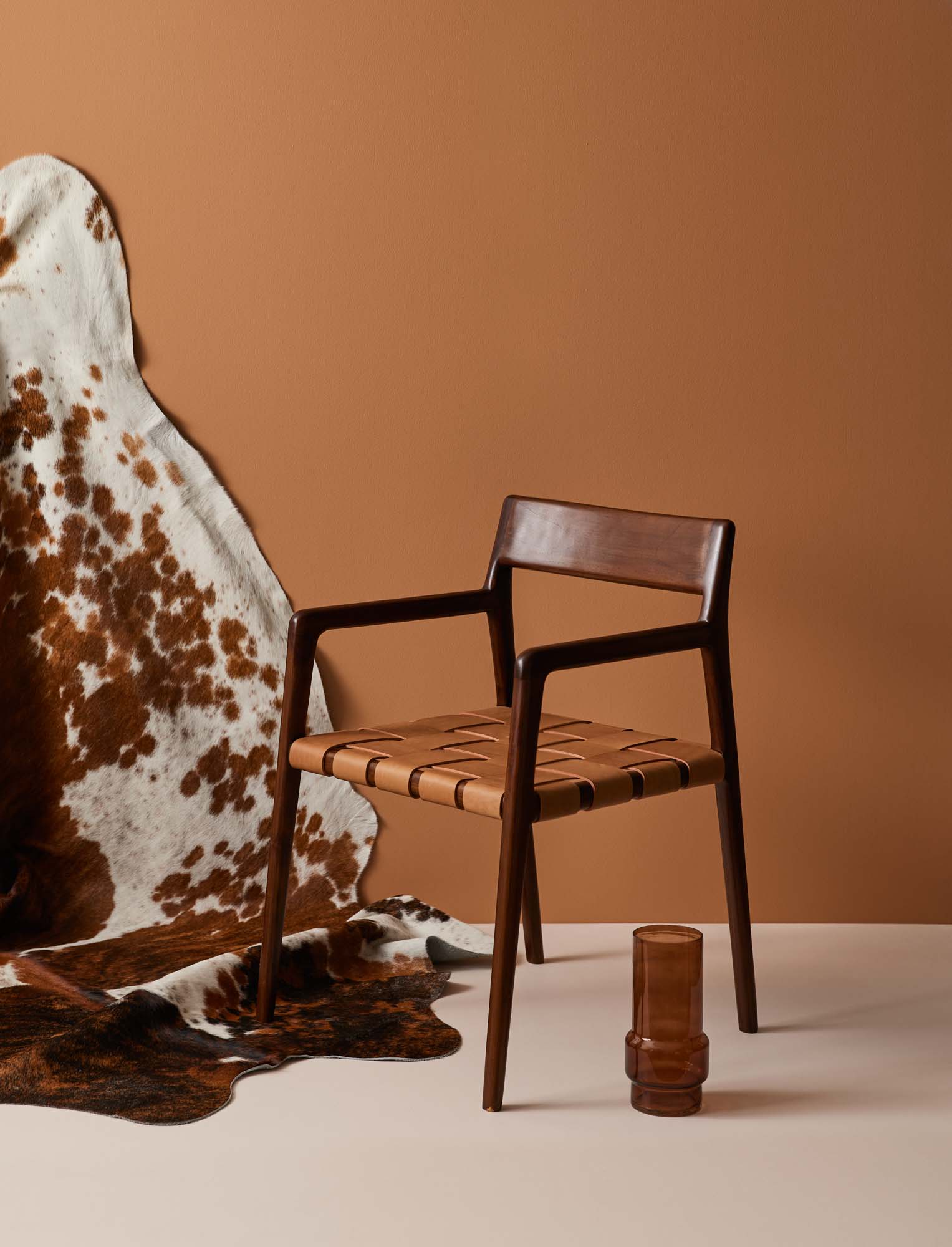 Image with brown wall, cowhide rug and walnut chair and cinnamon vase