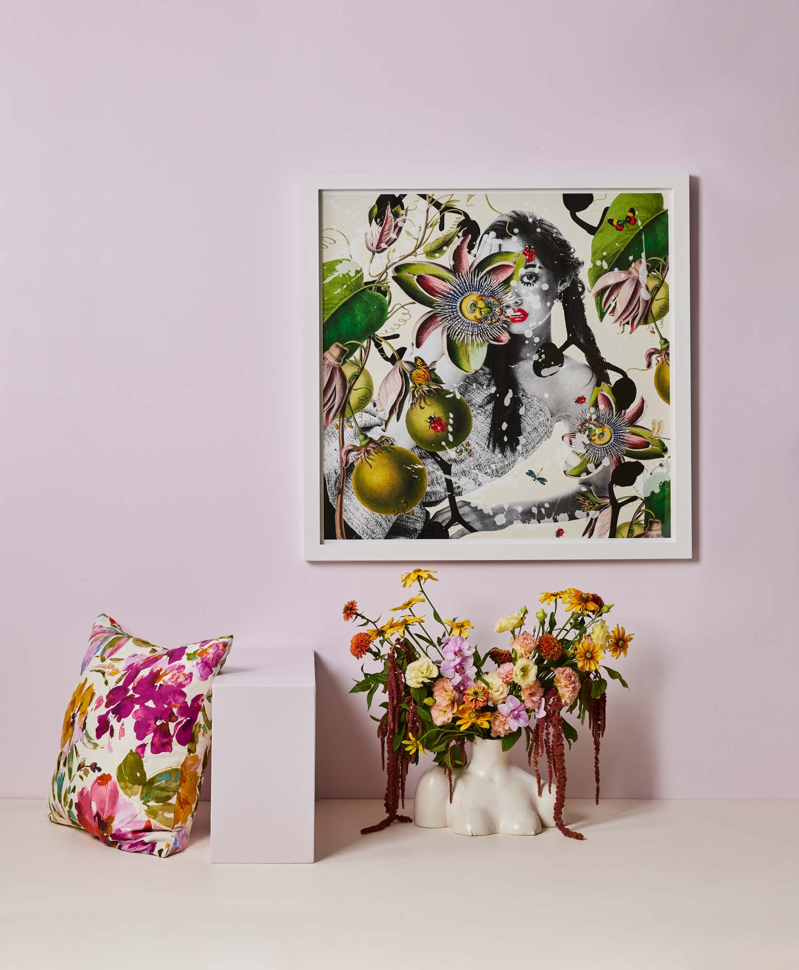 pink wall with botanical print on it, botanical cushion and a vase with floral arrangement