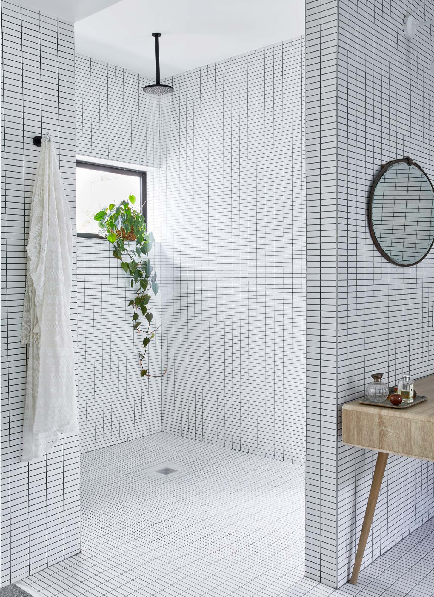 A large square walk in shower with kit kat white tiles all around it