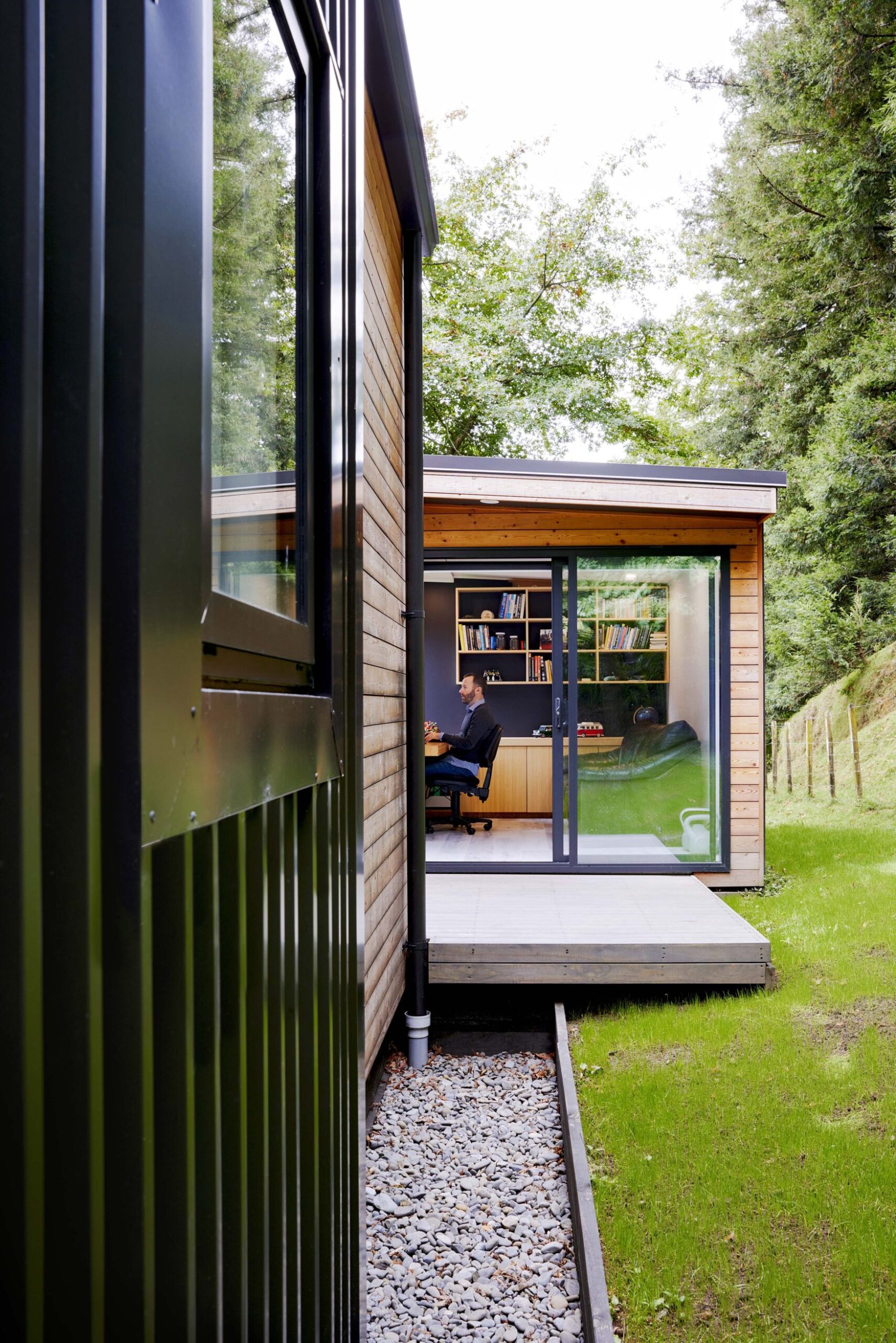 The exterior of a black house showing a living space through a large open window