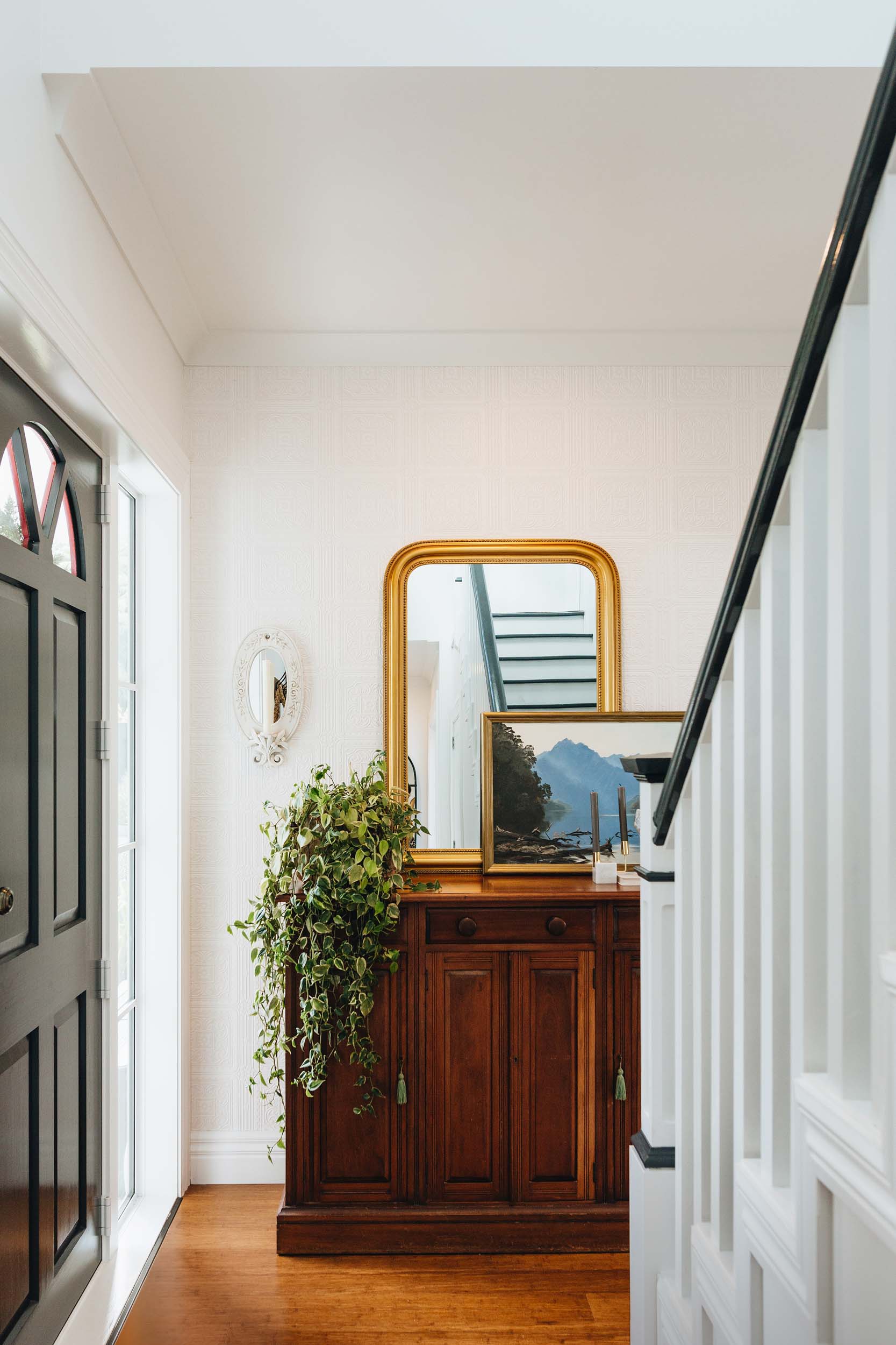 Entry way, with a cabinet that has a mirror and painting leaning against the wall