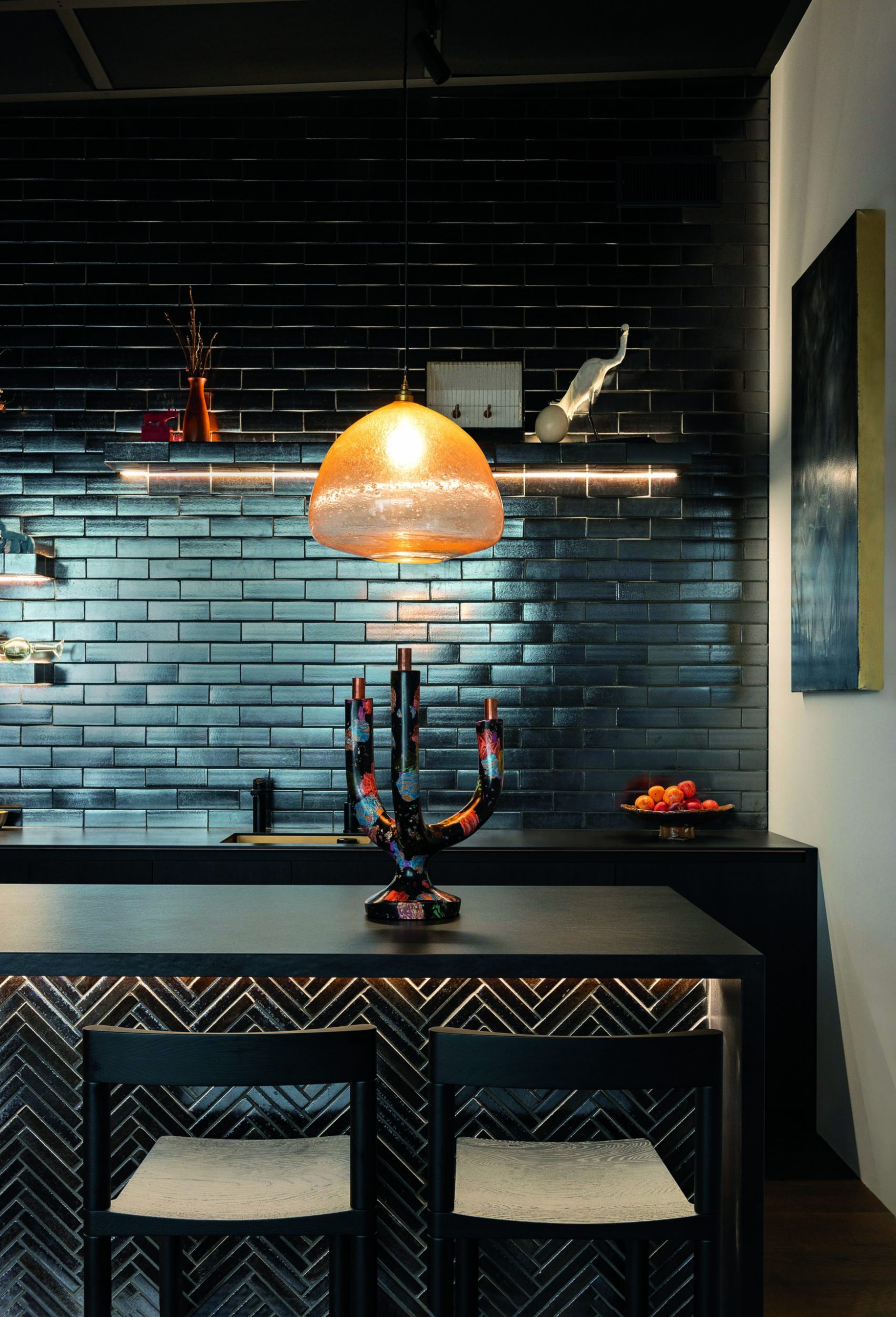 Kate Rutecki's black candle stick sitting on the island of and all black kitchen